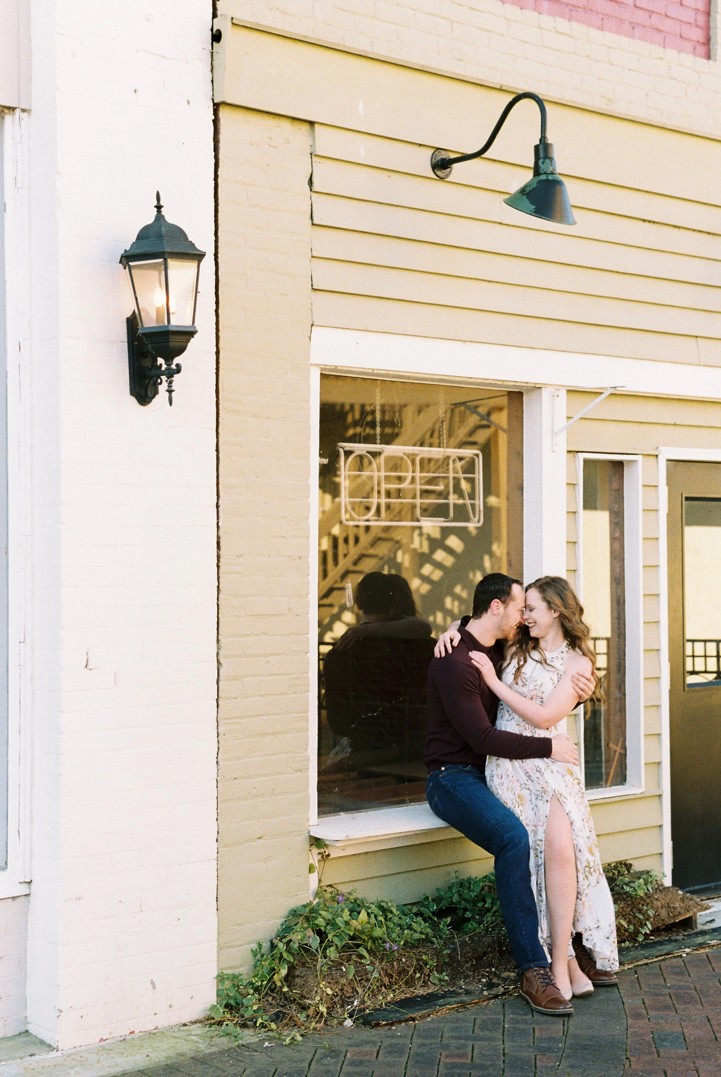 Maddie leans against a storefront window ledge as Conner embraces her in downtown Dallas, Georgia.
