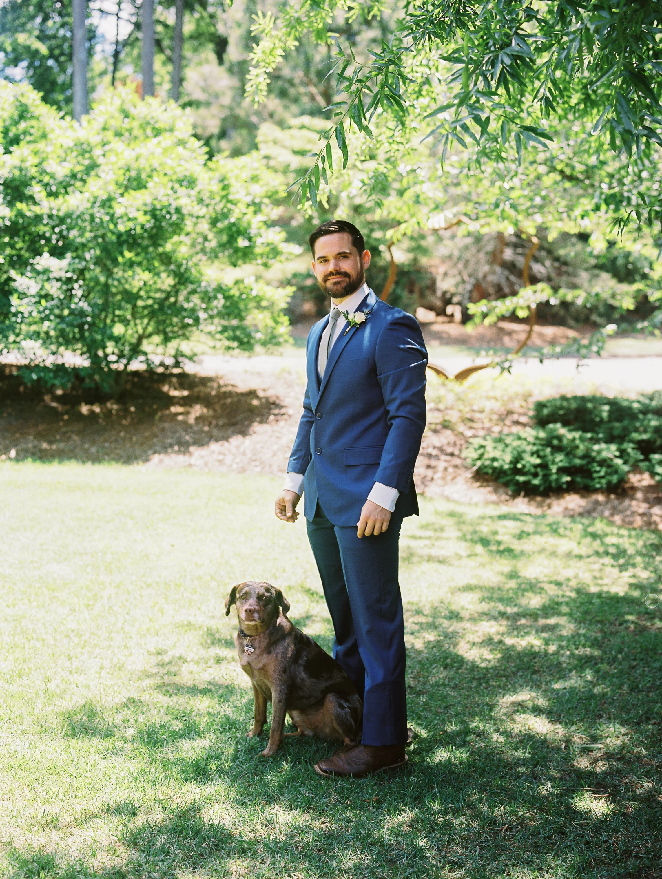 Groom standing on the lawn with Dakota, the couple's dog and wedding guest of honor