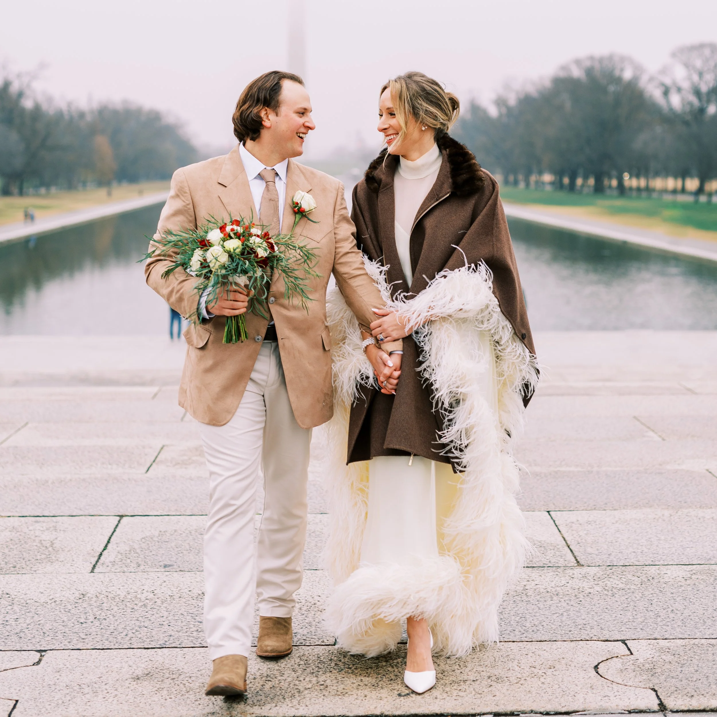Bride and groom walking hand in hand along the steps near the reflecting pool