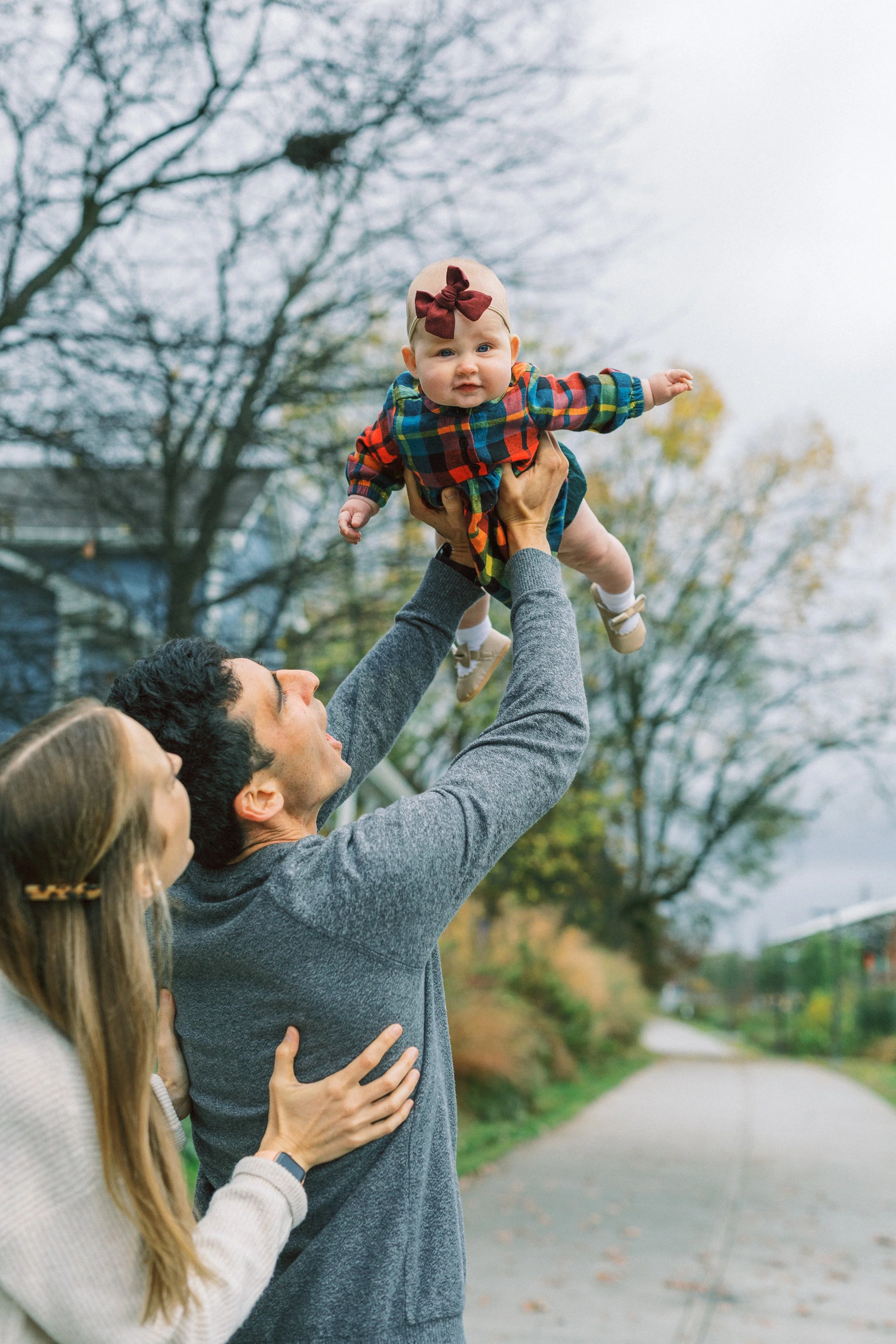 Dad joyfully lifting his baby girl into the air while mom watches, Reynoldstown, Atlanta, Georgia