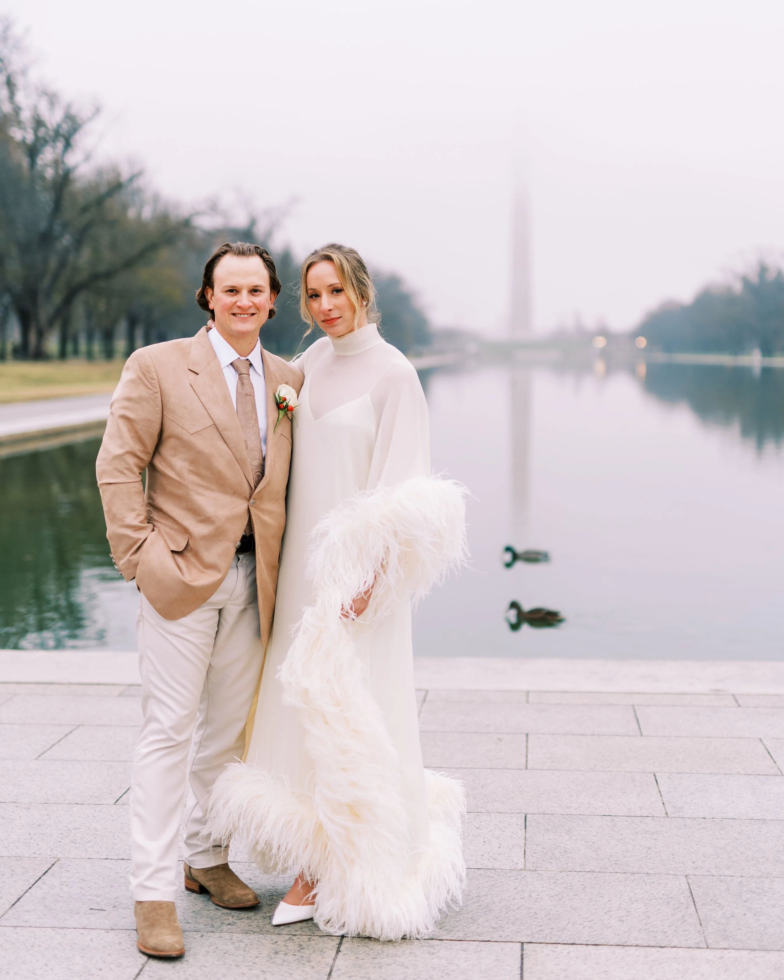 Bride and groom posing together with the Washington Monument reflected in the water behind them