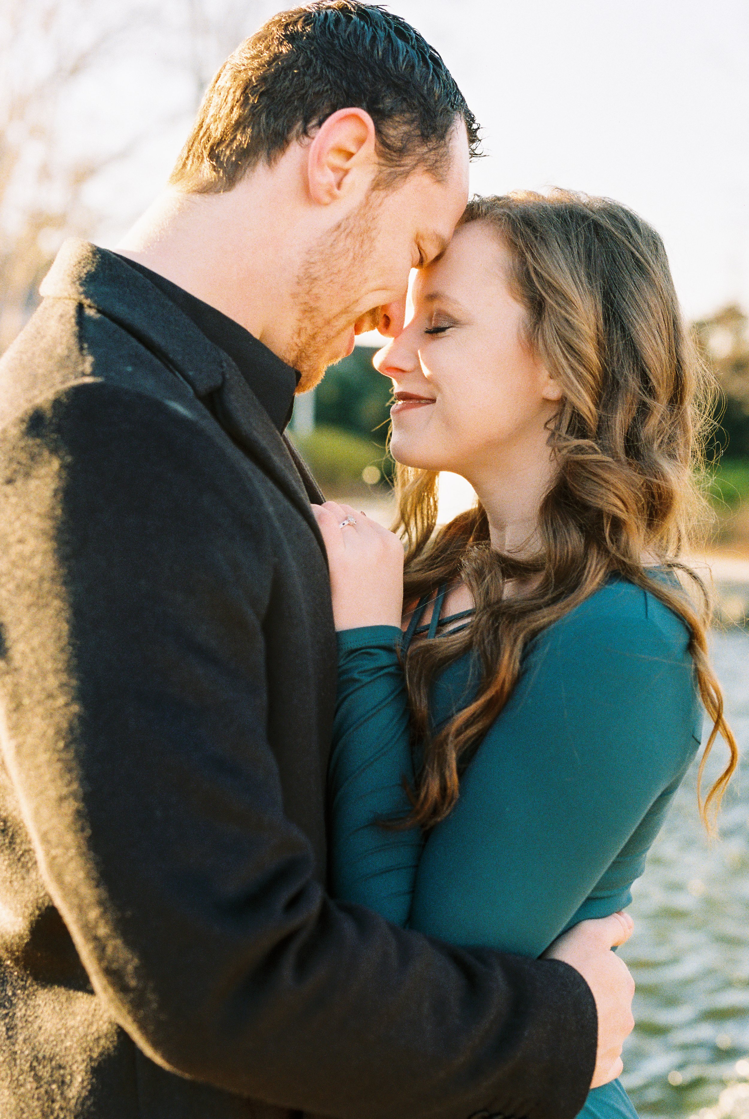 Conner and Maddie embrace forehead to forehead beside the water at sunset in Dallas, Georgia.