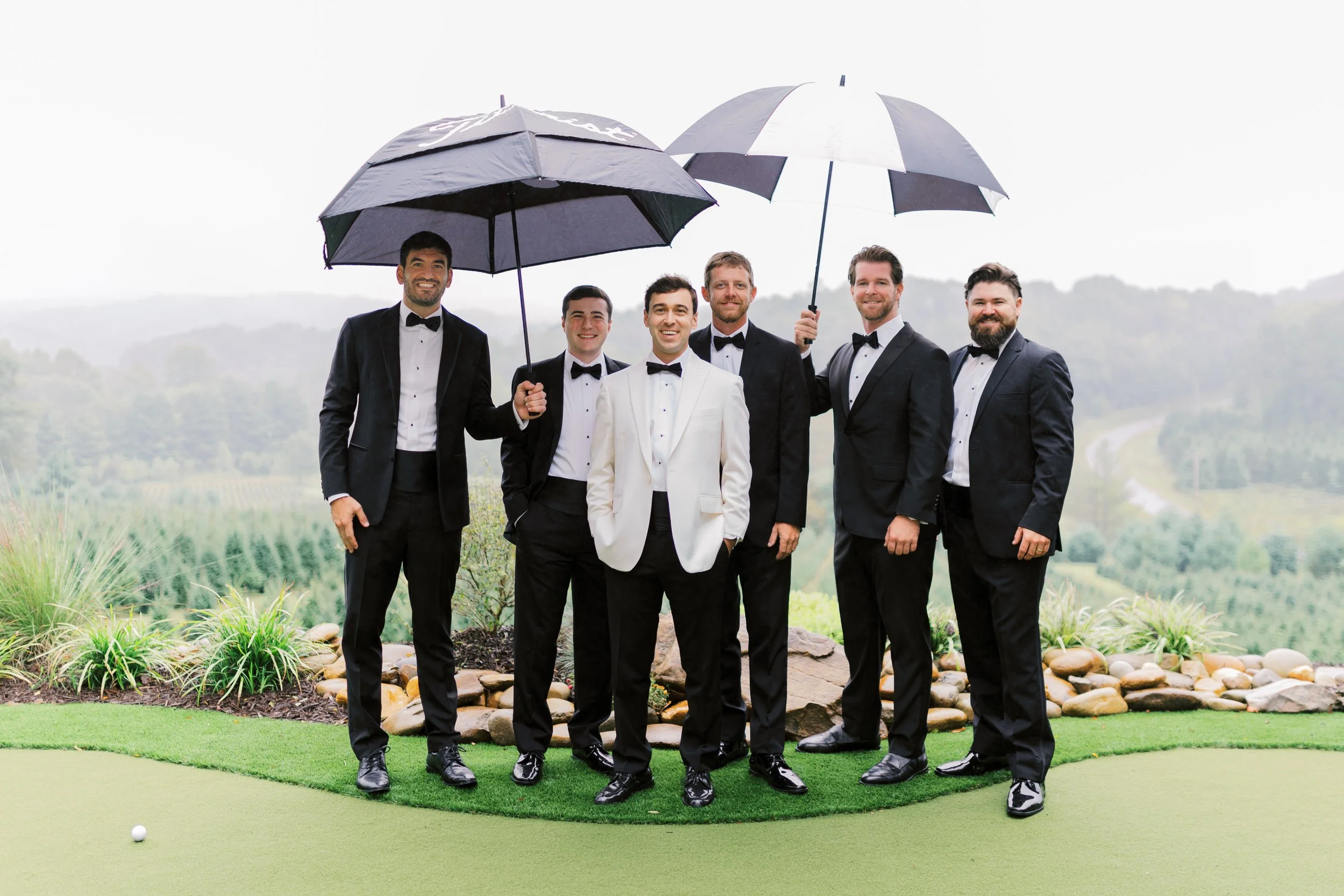 Groomsmen group portrait with umbrellas on the golf green