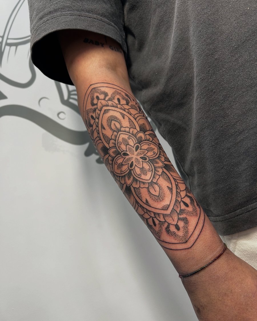 A tattoo sleeve on a person's arm featuring floral and ornamental designs.