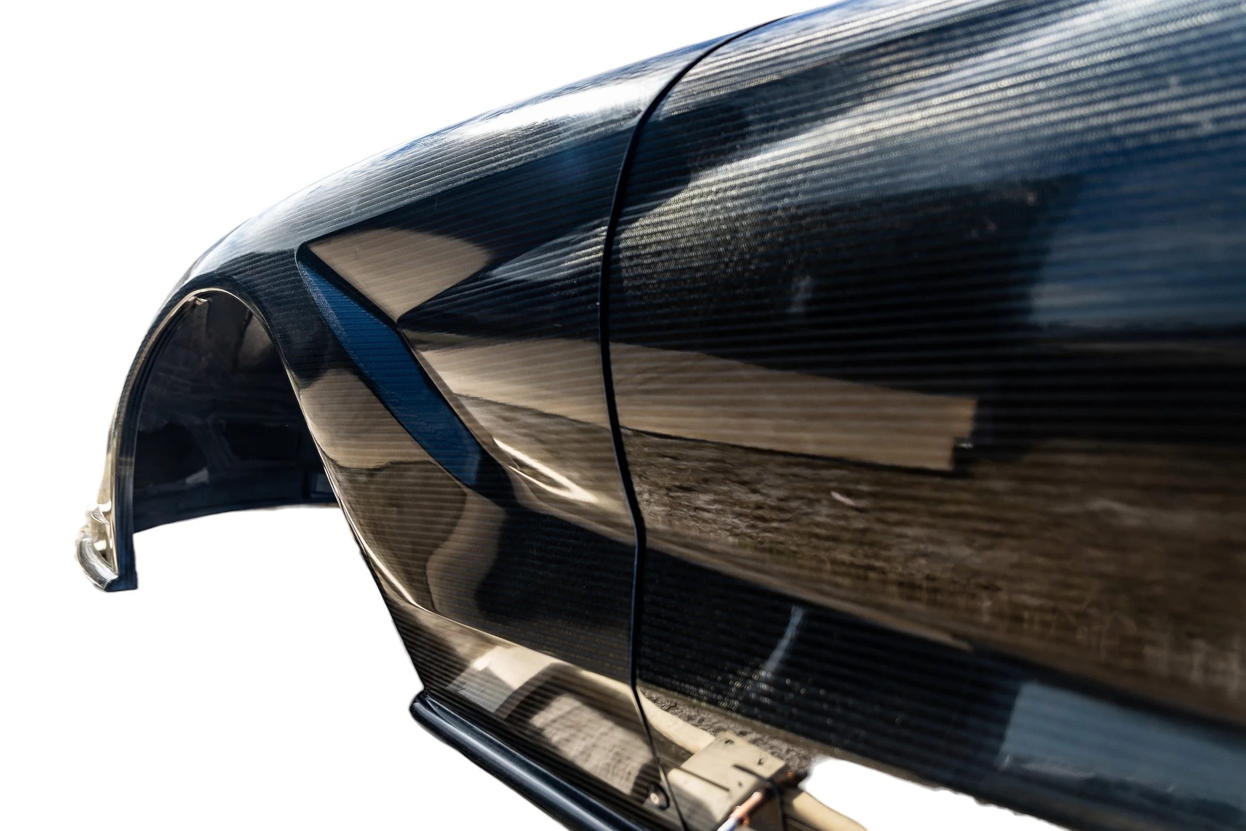 Close-up of a sleek black carbon fiber car wheel arch and door panel.