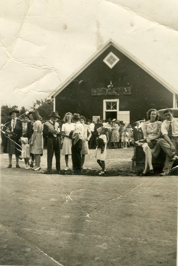 Black and white photo of a crowd of people, including children and adults, standing in front of Acadia Hall in Sackville, NS in the 1920s. The scene appears to be outdoors during daytime.