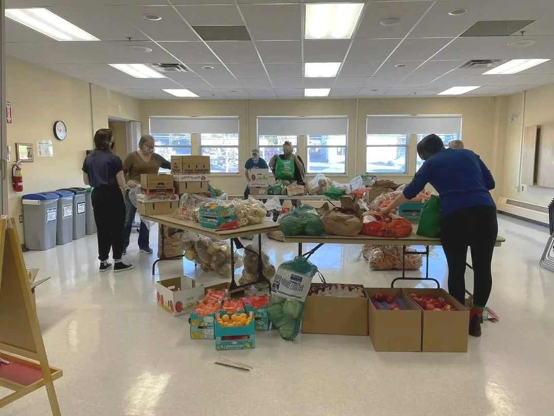 People packing boxes of food in a community center or donation drive setting.