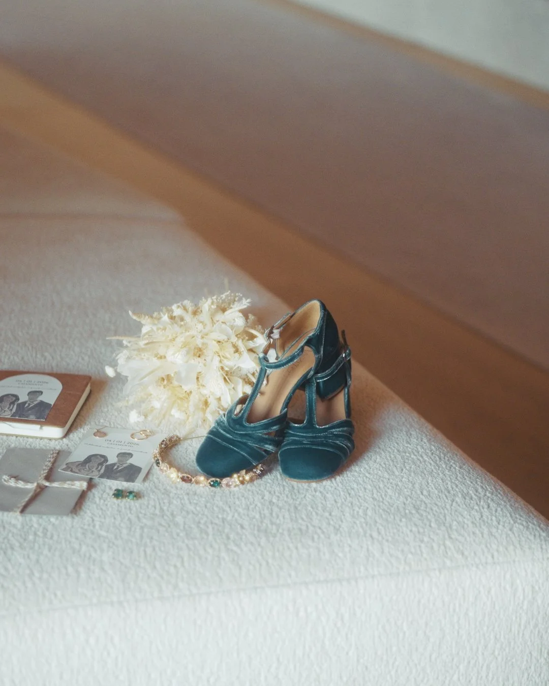 Sapatos de veludo azul, bouquet branco e acessórios de casamento preparados no quarto da noiva.