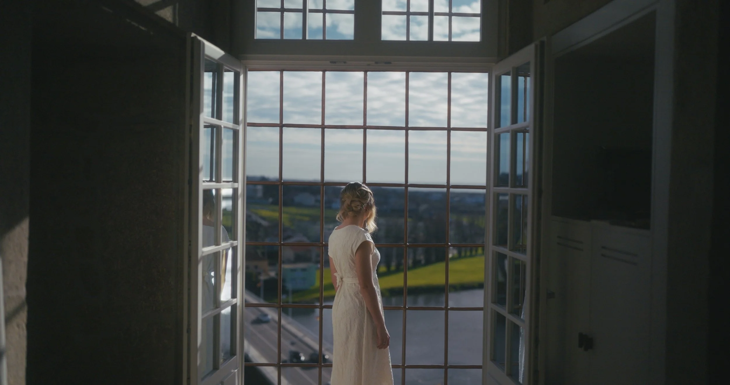 Noiva junto a uma janela de grandes dimensões com vista sobre Vila do Conde no dia do casamento.
