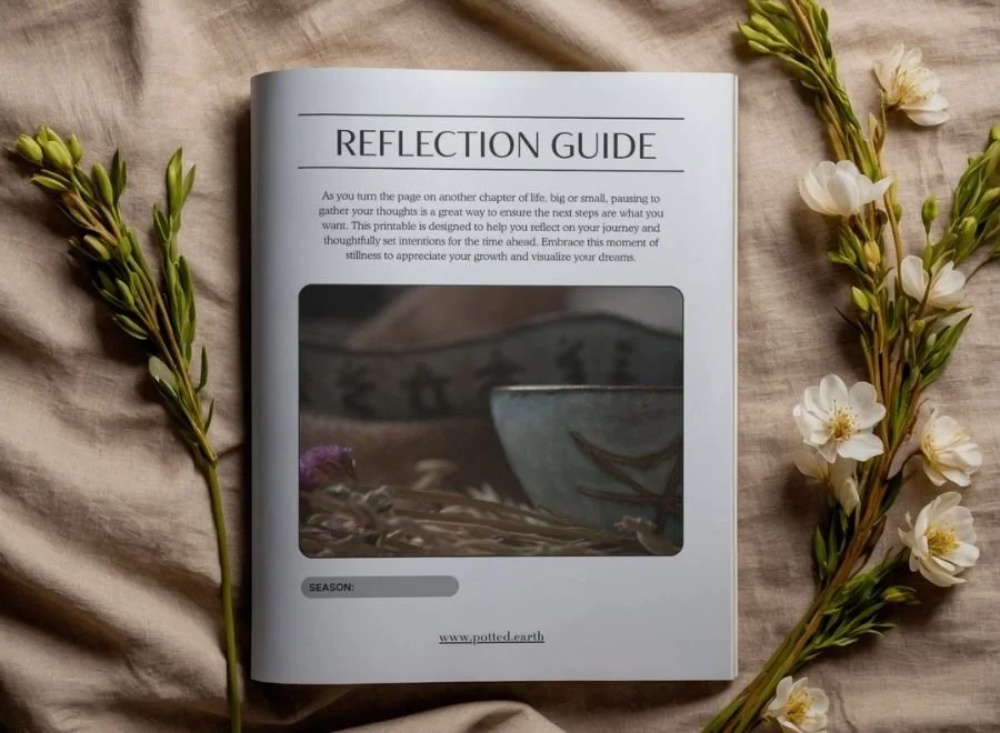 Open magazine page titled "Reflection Guide" surrounded by white flowers and green sprigs on a beige fabric background.