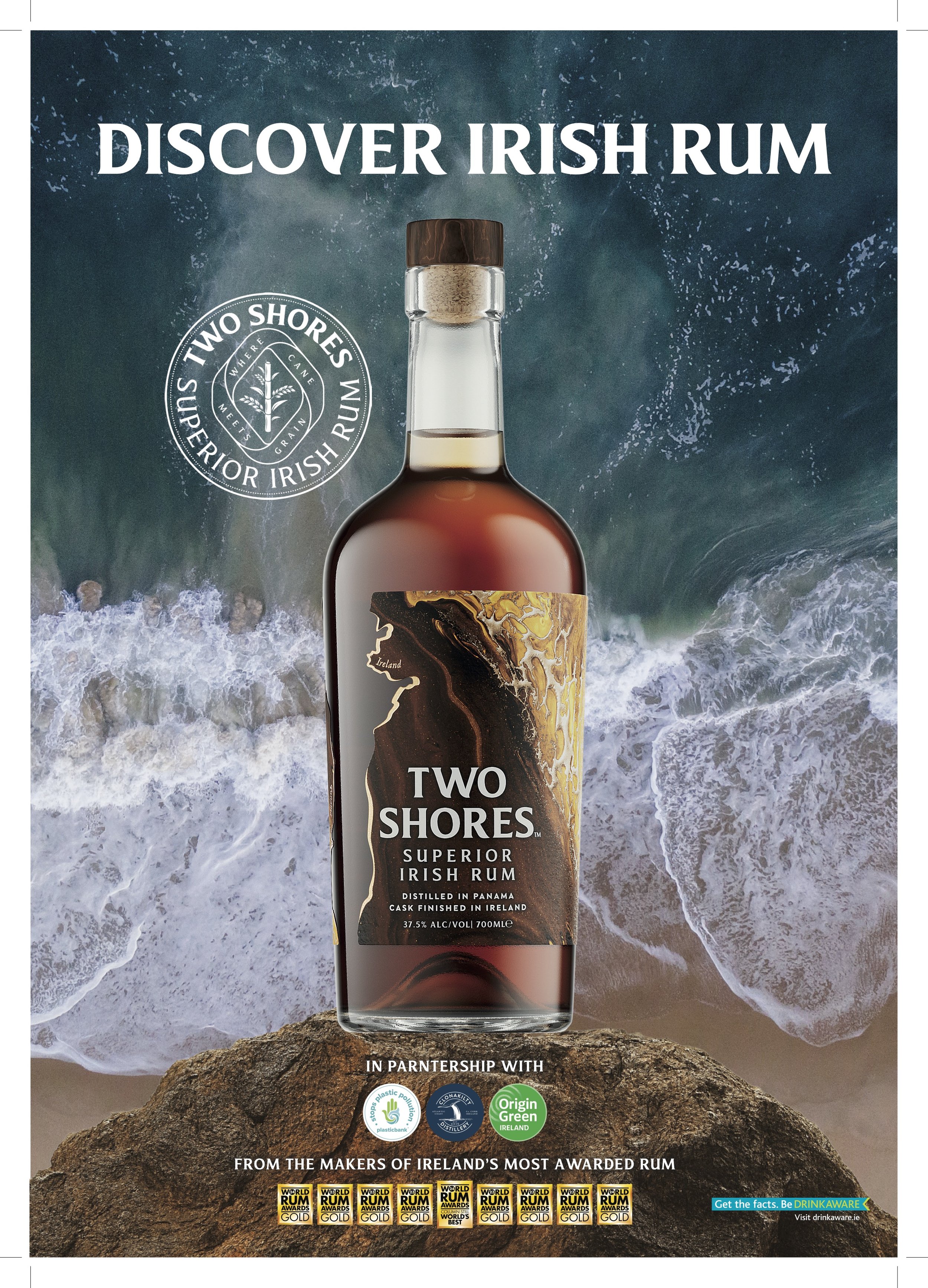 Advertentie voor Irish Rum genaamd Two Shores, met een rumfles op een rots en een achtergrond van de zee en golven.