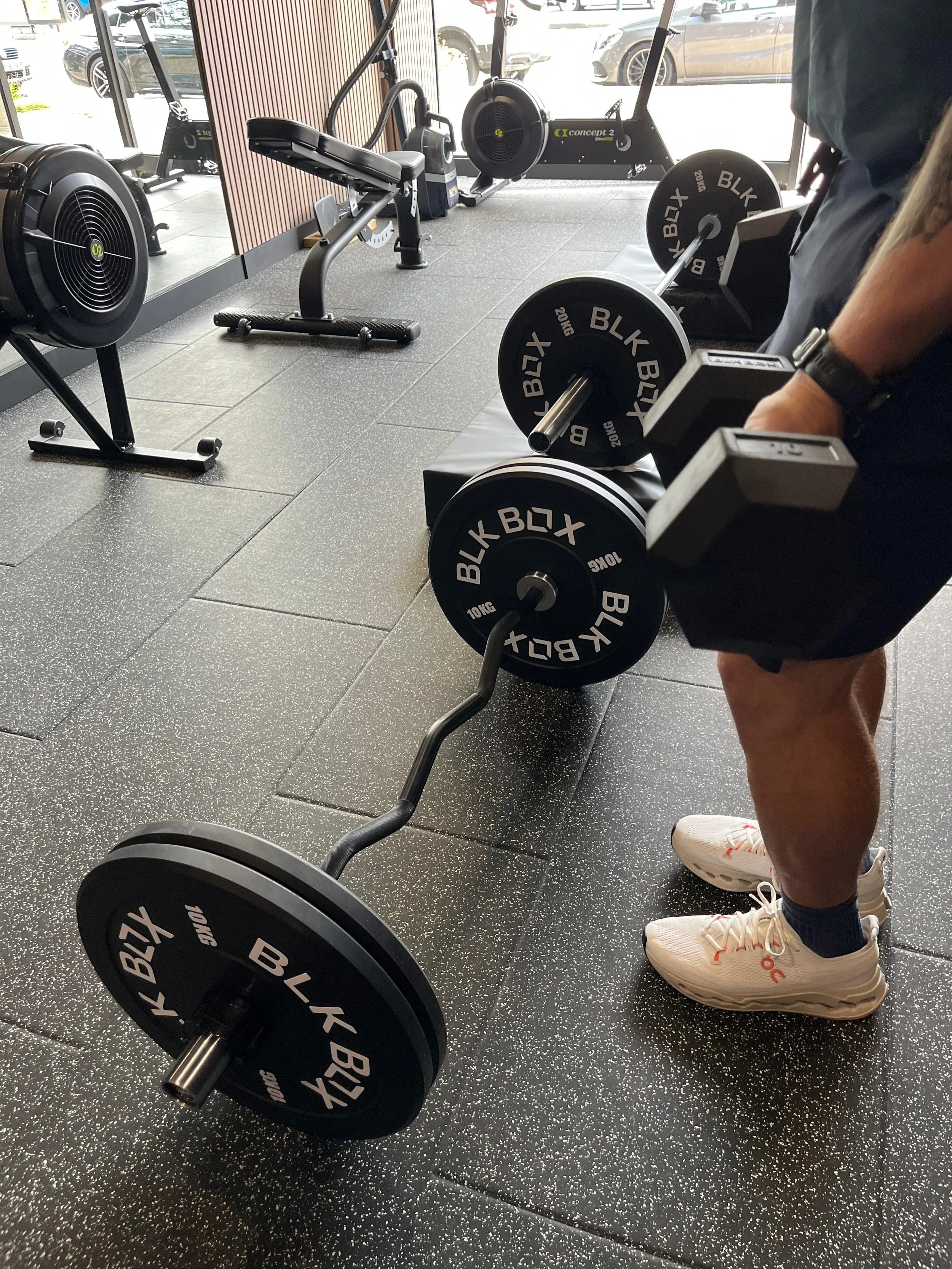 Person lifting dumbbells in a gym with various exercise equipment in the background.