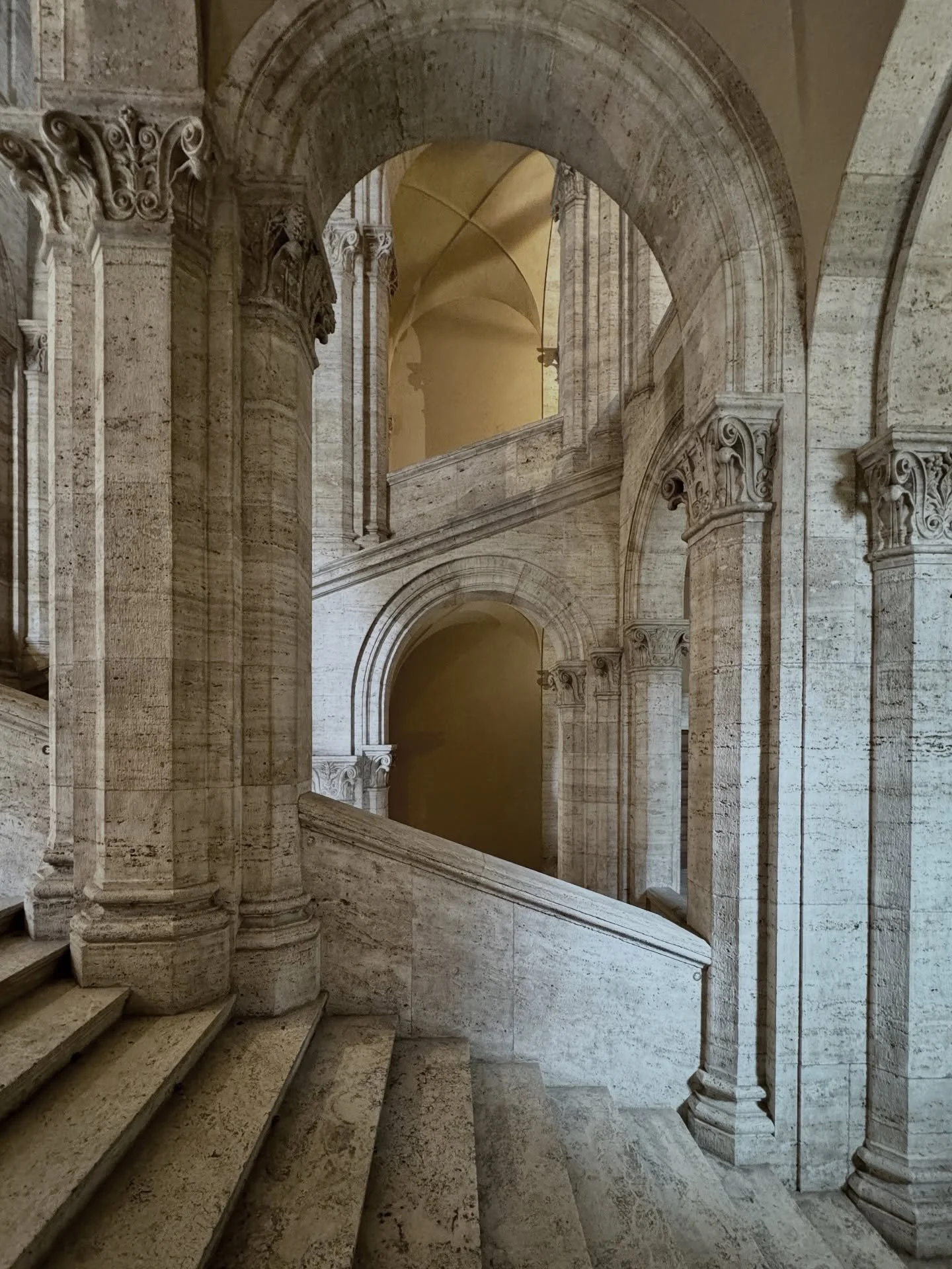 Inside Palazzo Venezia, history ascends in stone. Elegant arches and sculpted columns frame a silent harmony of light, shadow, and time. Each step echoes Renaissance grandeur &mdash; an architectural masterpiece where artistry, heritage, and timeless