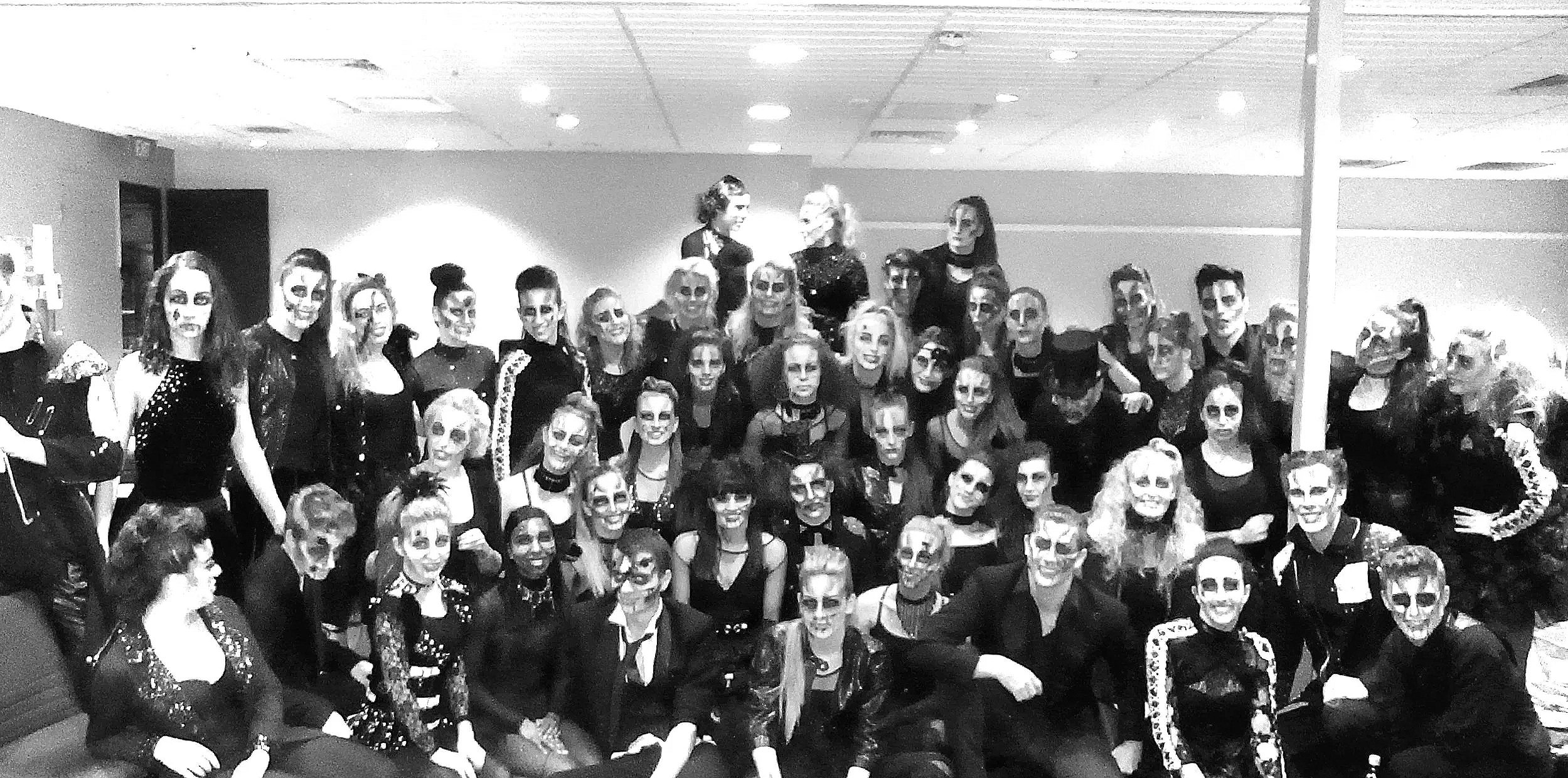 Group of people dressed in skeleton and zombie makeup, celebrating Halloween in an indoor setting.