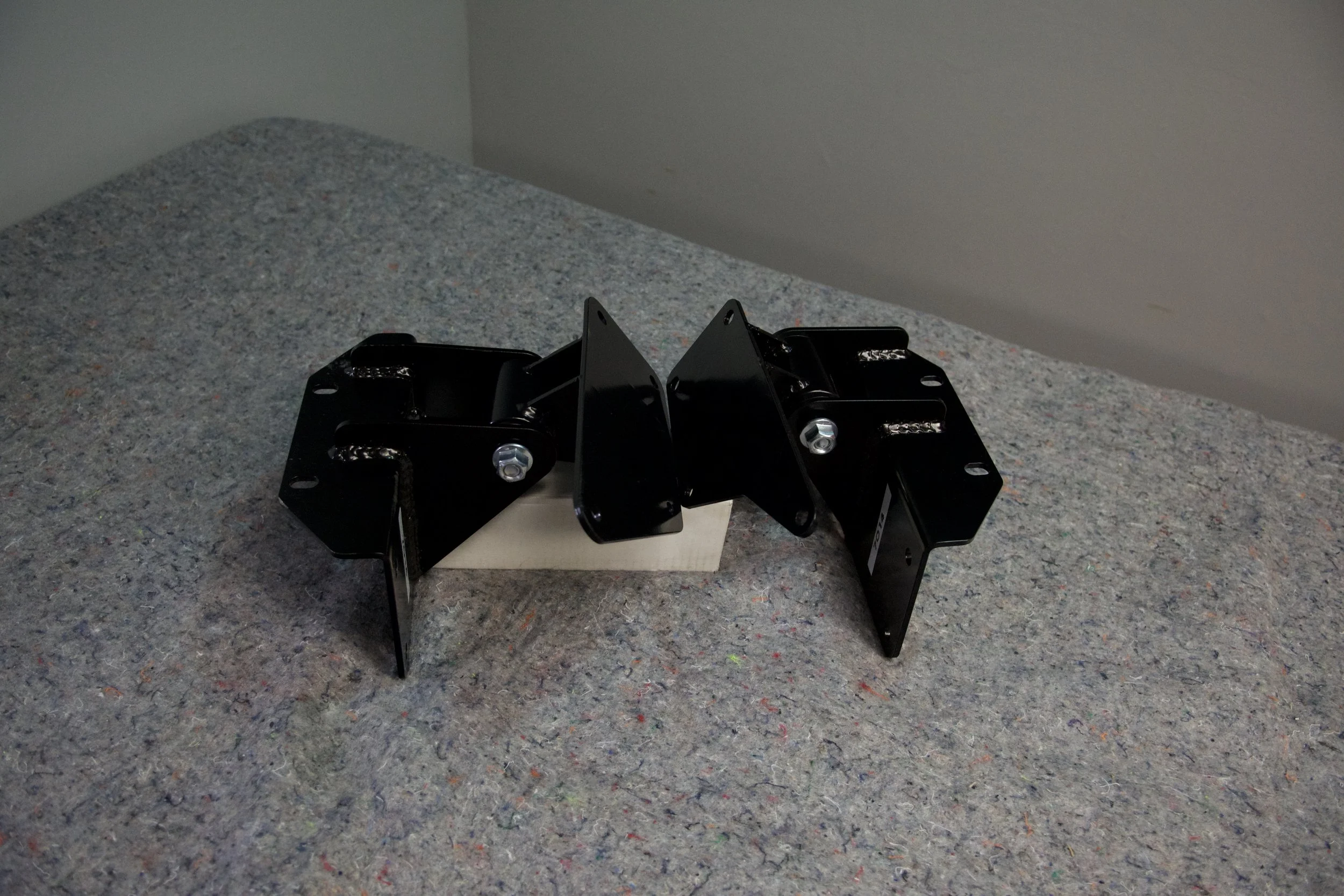 Close-up of Gen2 Ford Bronco/F150 7.3L Godzilla engine mount kit installed, showing frame and engine side mounts for coil spring suspension.