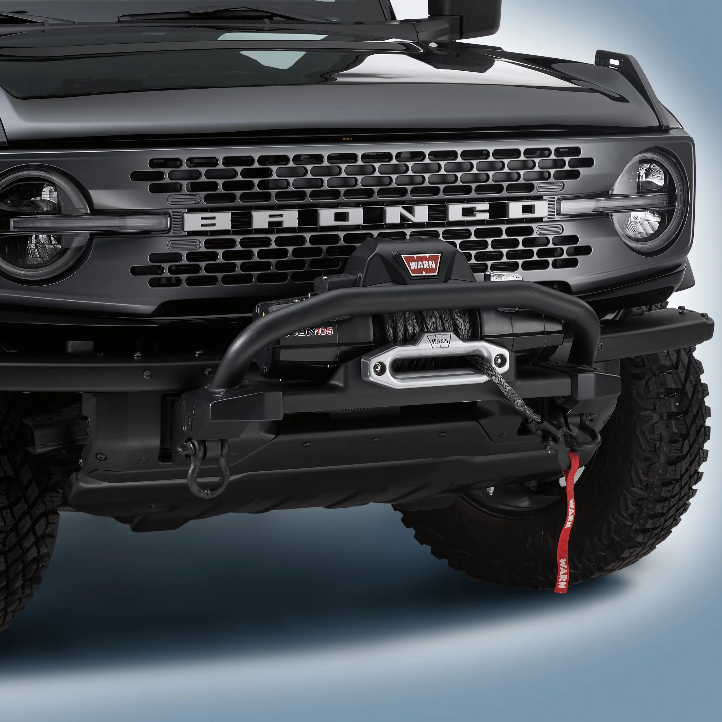 Brand new WARN winch kit for Ford Bronco (PN: M-1821-B) shown complete in original packaging, with synthetic rope, hardware, and remote controller.