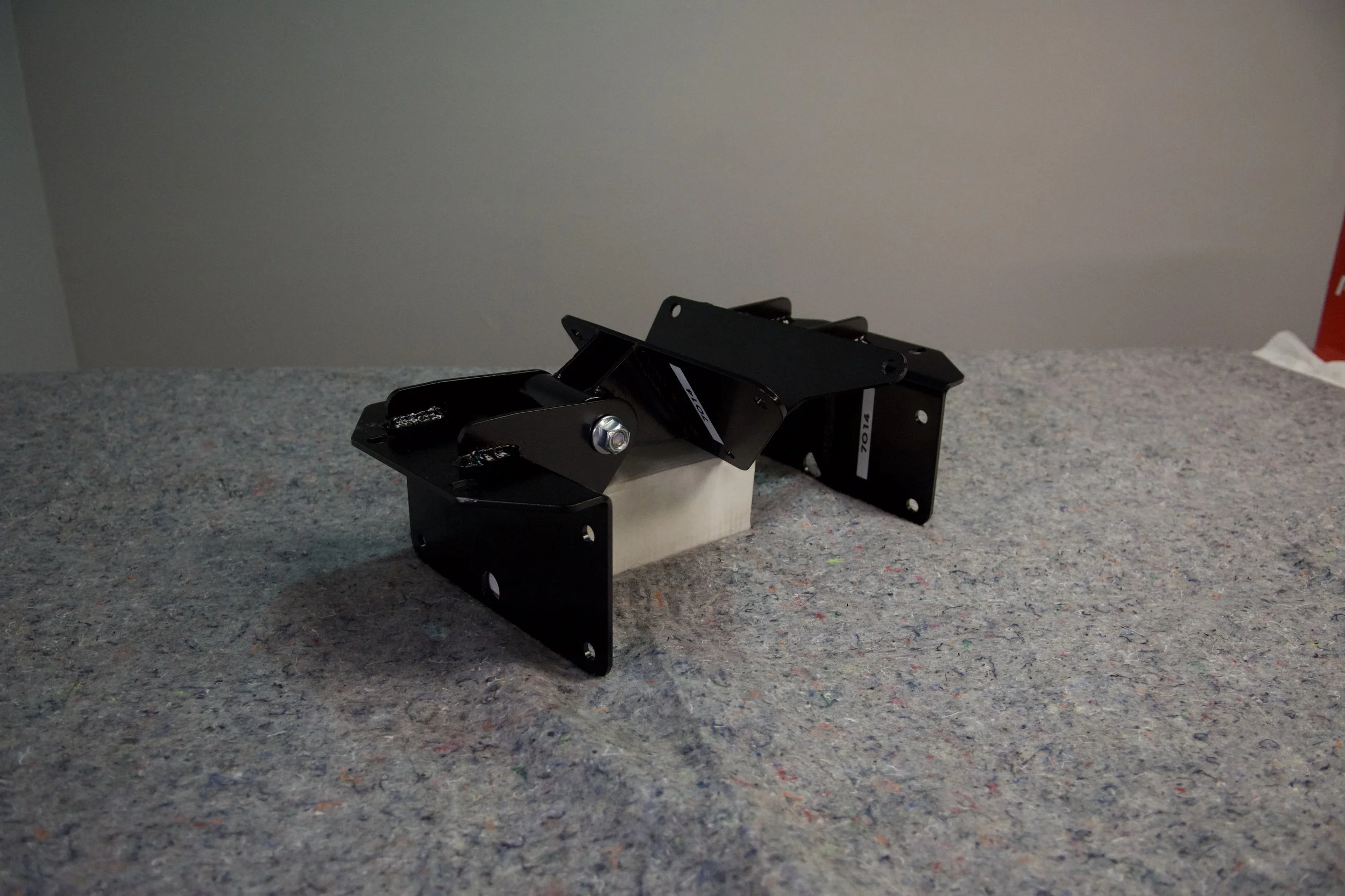 Close-up of Gen2 Ford Bronco/F150 7.3L Godzilla engine mount kit installed, showing frame and engine side mounts for coil spring suspension.