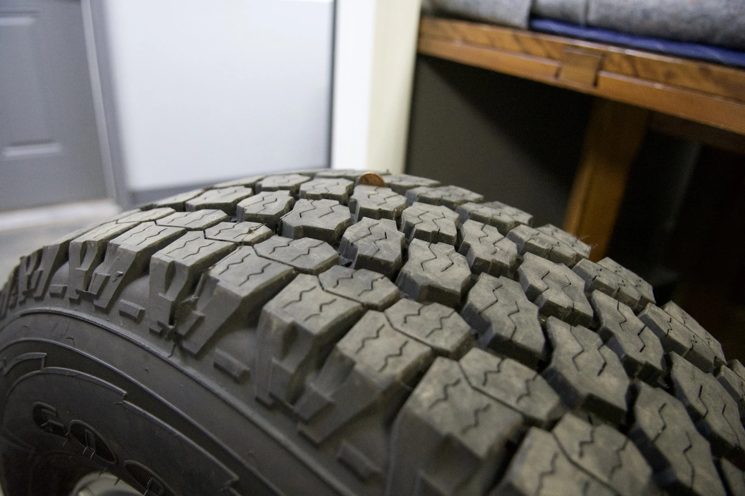 Brand new Goodyear Wrangler All-Terrain Adventure tire mounted on silver multi-spoke alloy rim, ready for 4x4 trucks or classic Bronco builds.