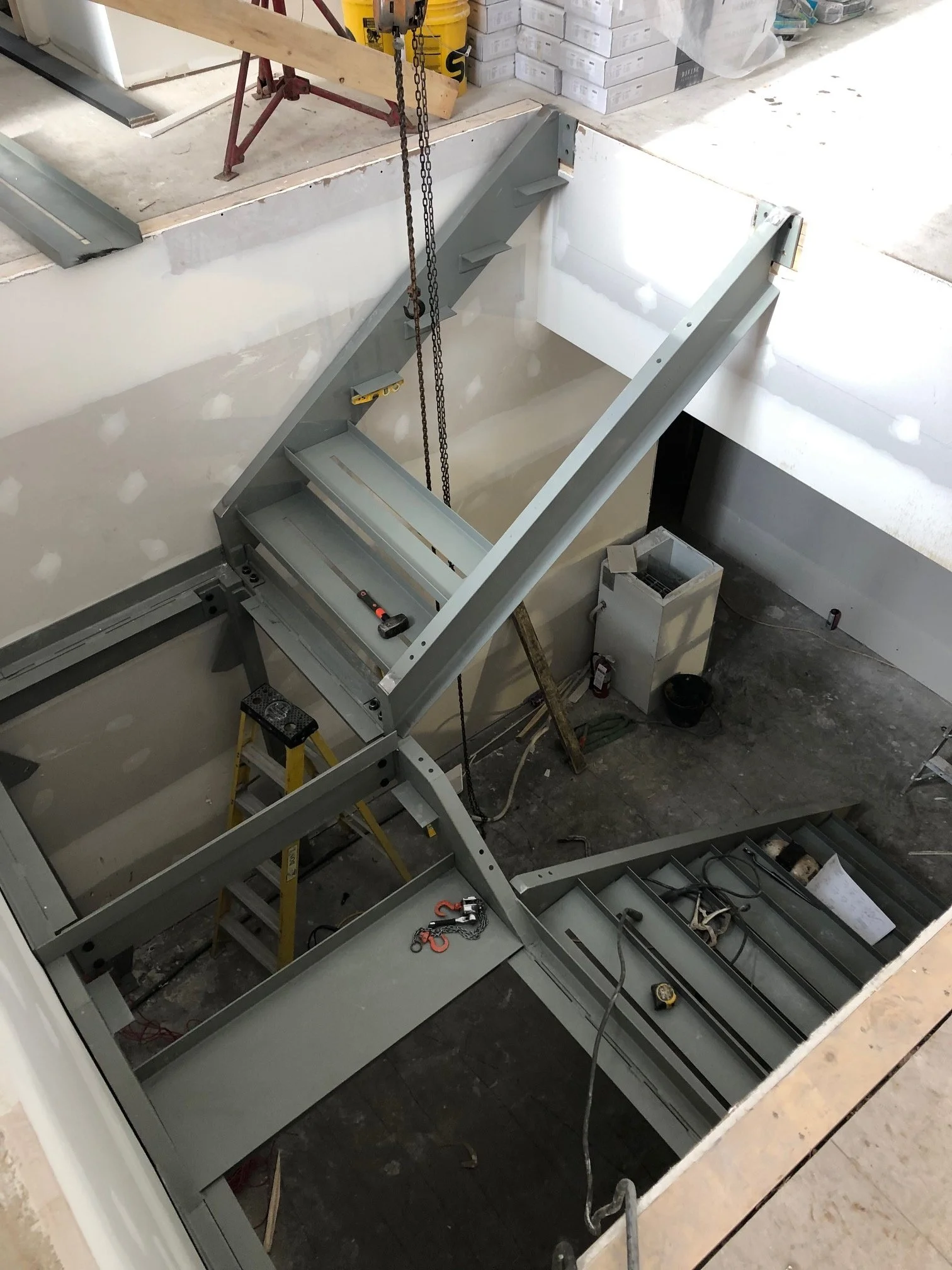 Construction site with metal framing and tools, possibly for a staircase or structural support installation.