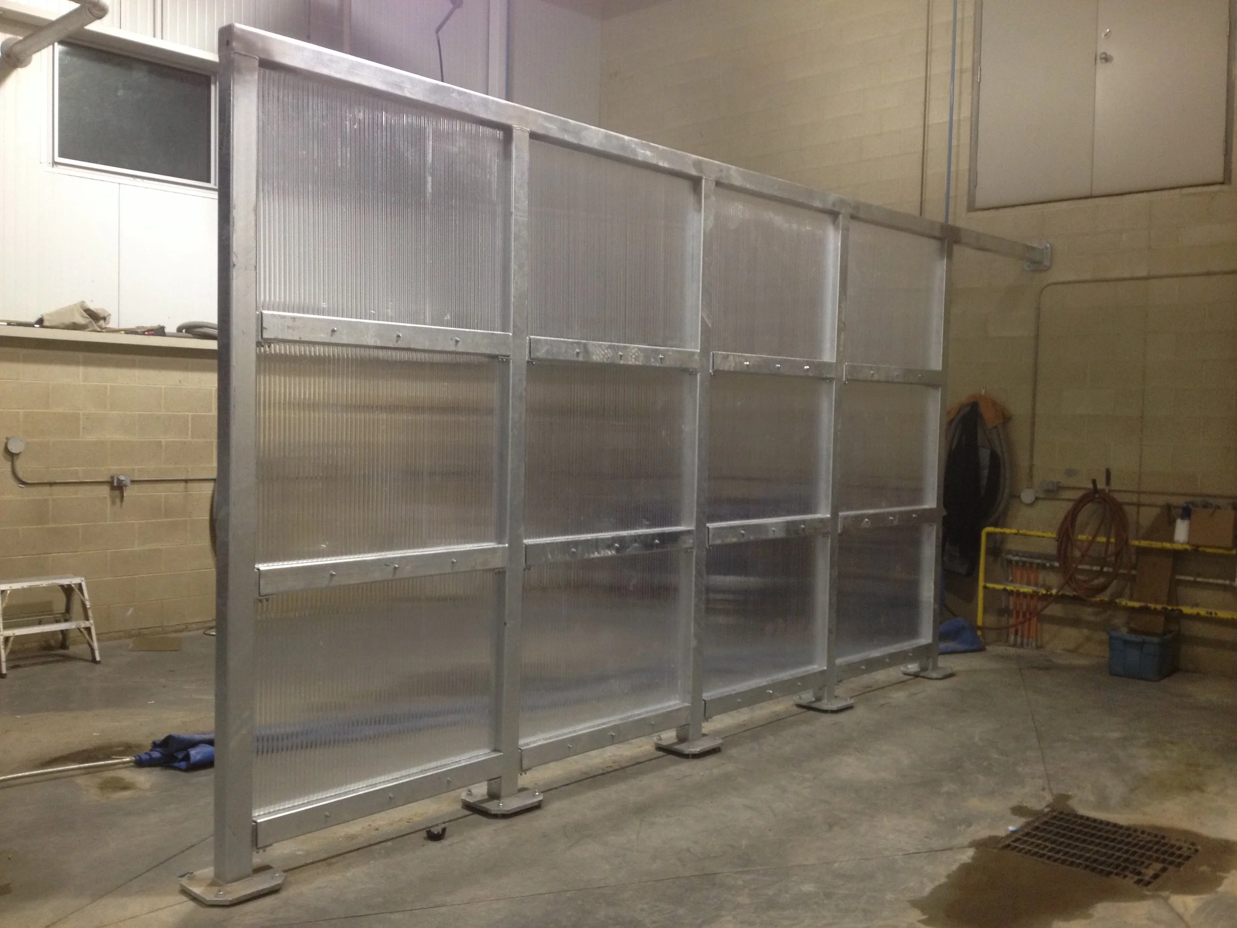 A large, transparent plastic and metal enclosure in an industrial or warehouse setting.