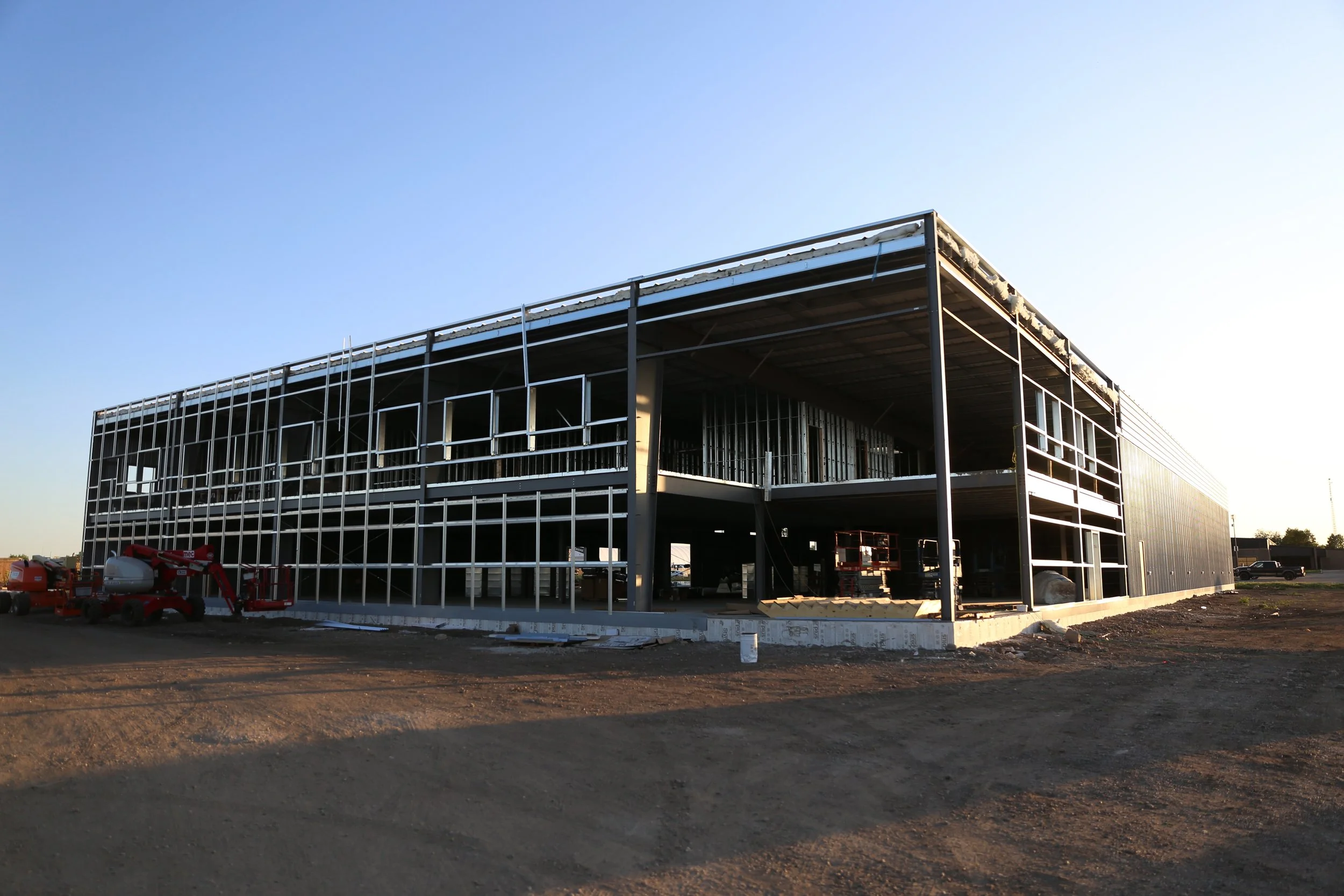 Construction site of a multi-story building with steel framing, partially built with some machinery and construction materials visible.