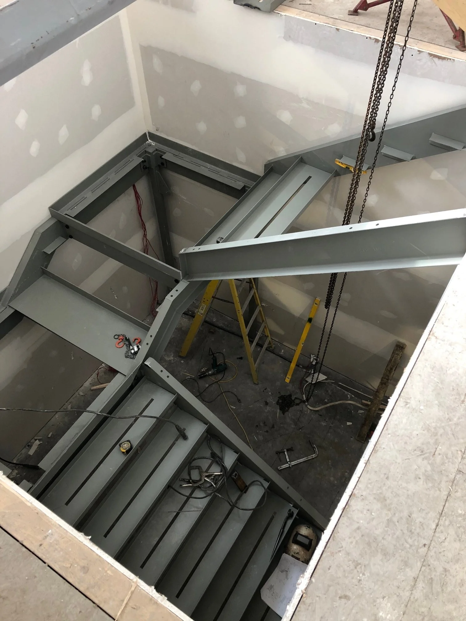 Construction site with steel framing and staircase in an indoor space under construction.