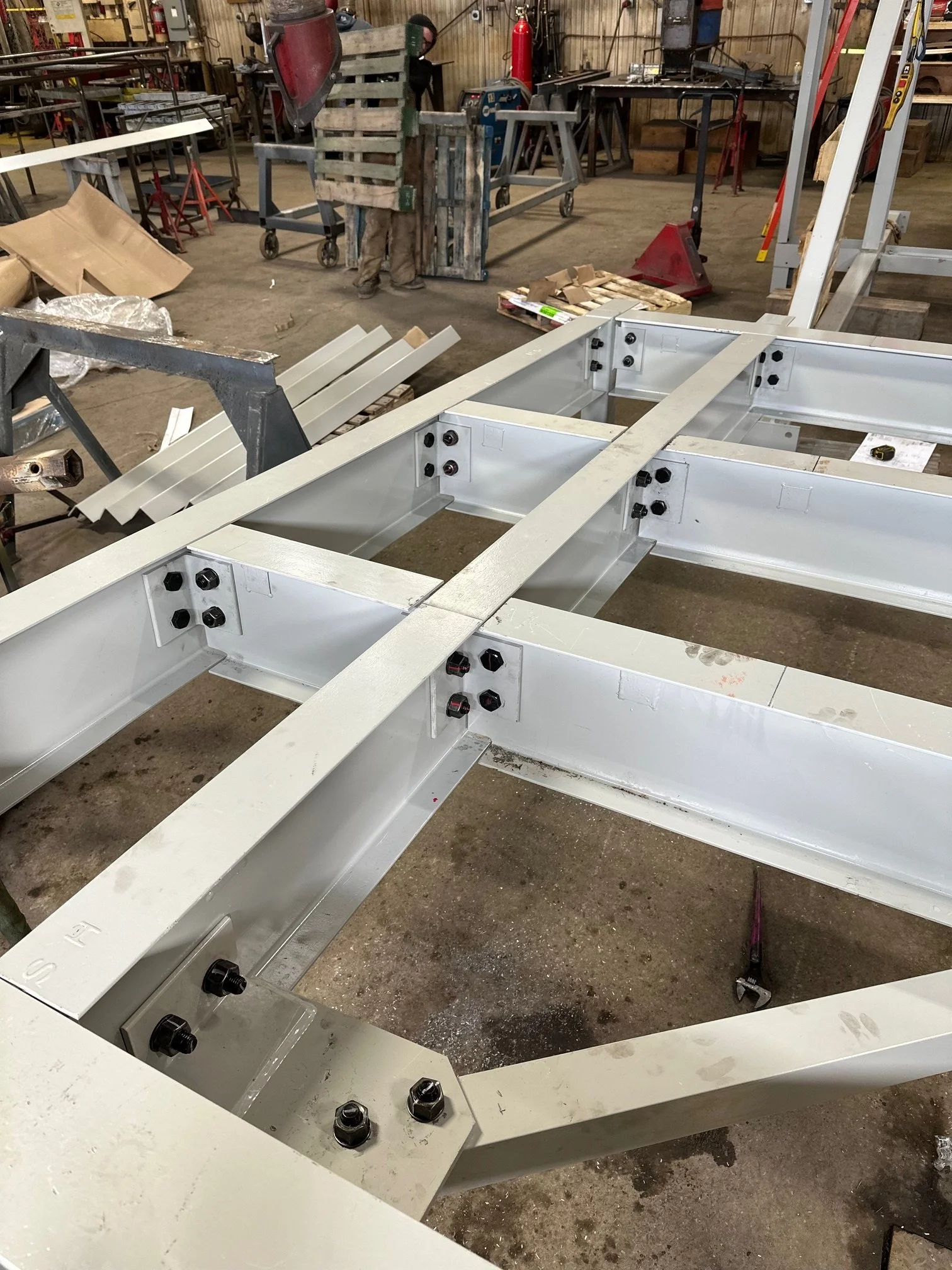 Metal framework being assembled in a workshop with tools and equipment around.