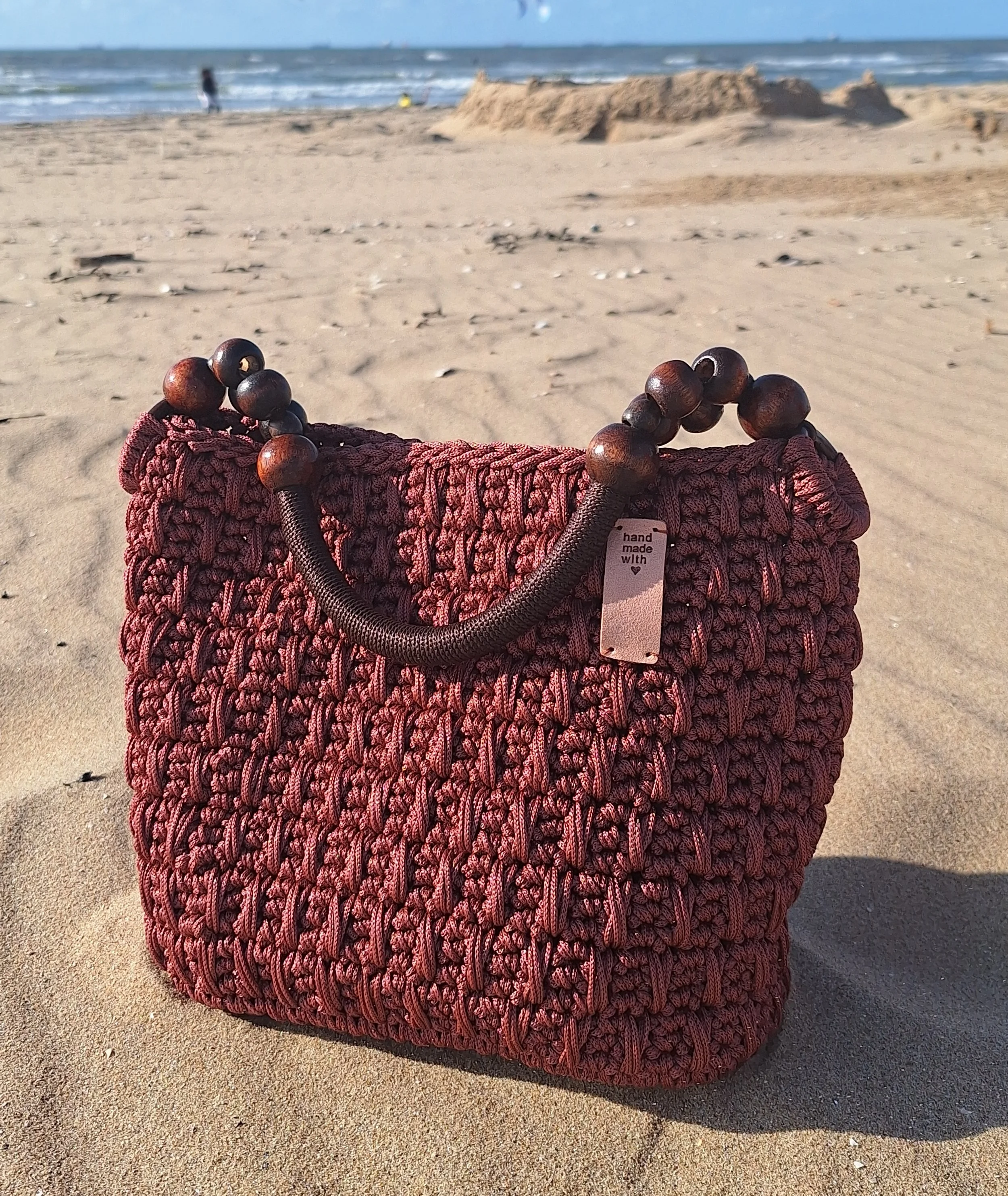 Handgemaakte Bagolu haaktas model Tina in bordeaux tinten, verbonden met de haakmissie in Abene, Senegal.