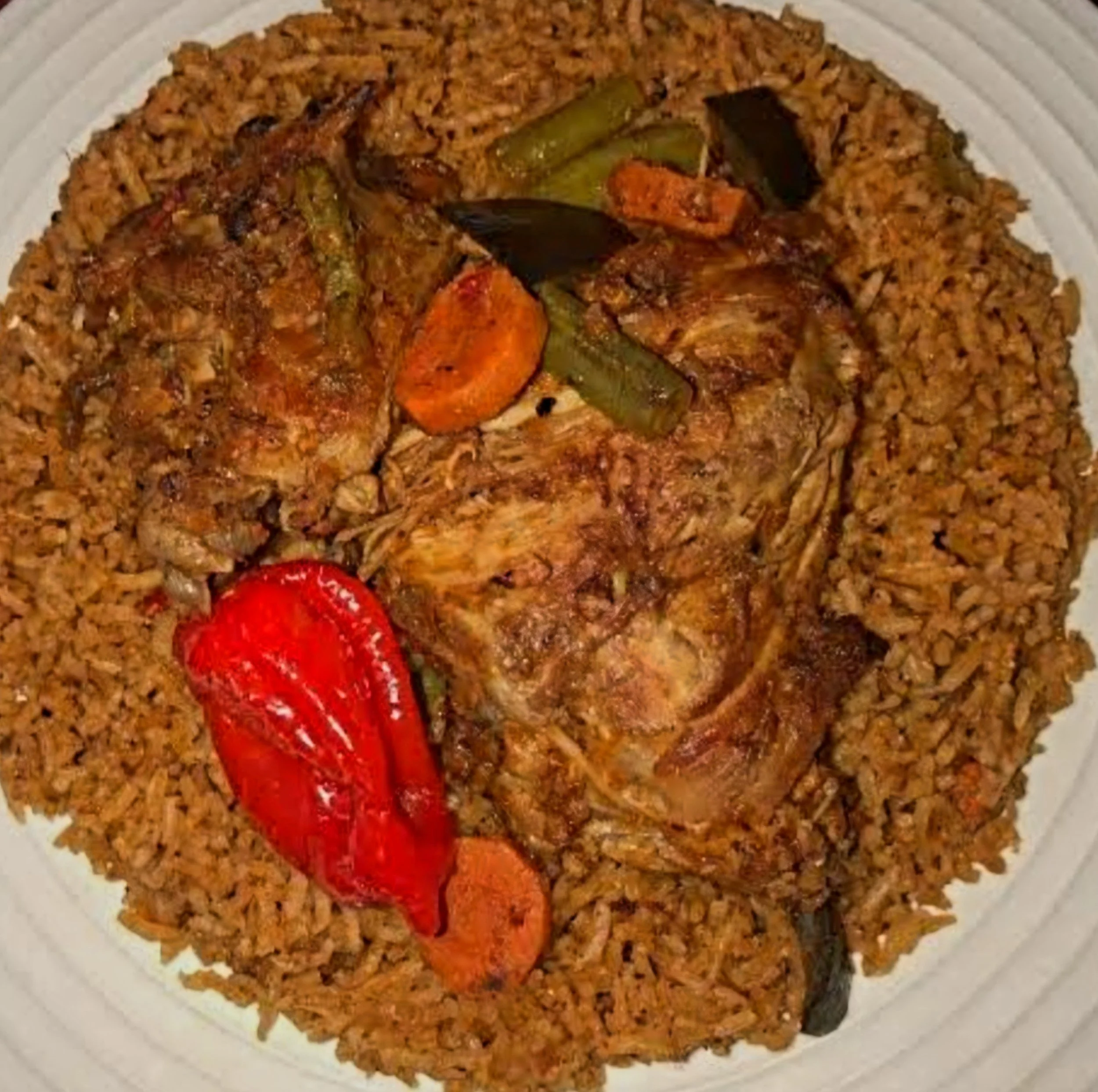 Traditional Benechin from Senegal with spiced rice, chicken, and vegetables served on a white plate.