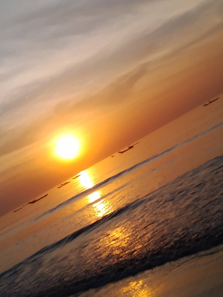 Zonsopgang boven de Atlantische Oceaan bij Abene in Senegal met vissersboten aan de horizon