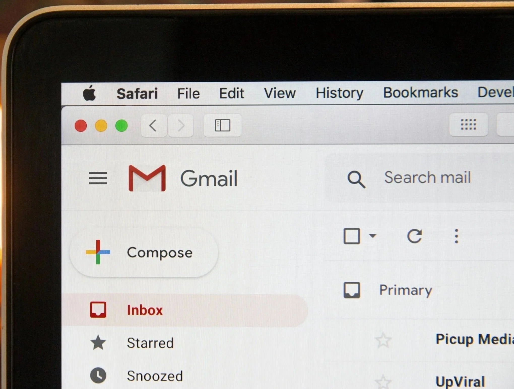 Screenshot of a Gmail inbox displayed on a MacBook screen, showing menu options and email labels in American English.