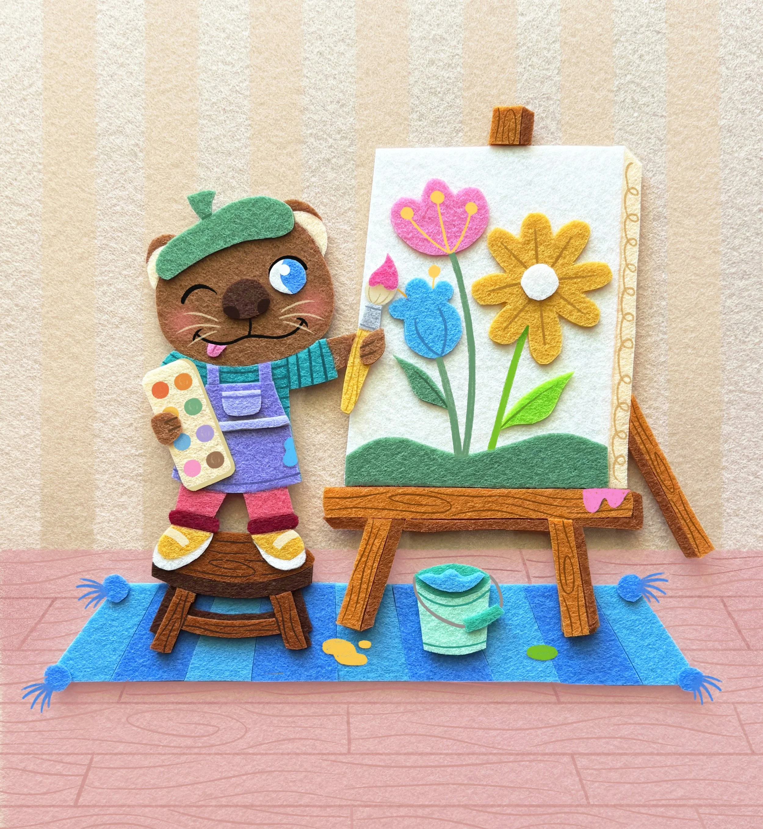 A felt illustration of an otter painting flowers onto a canvas on an easel. He stands on a brown stool over a blue rug.