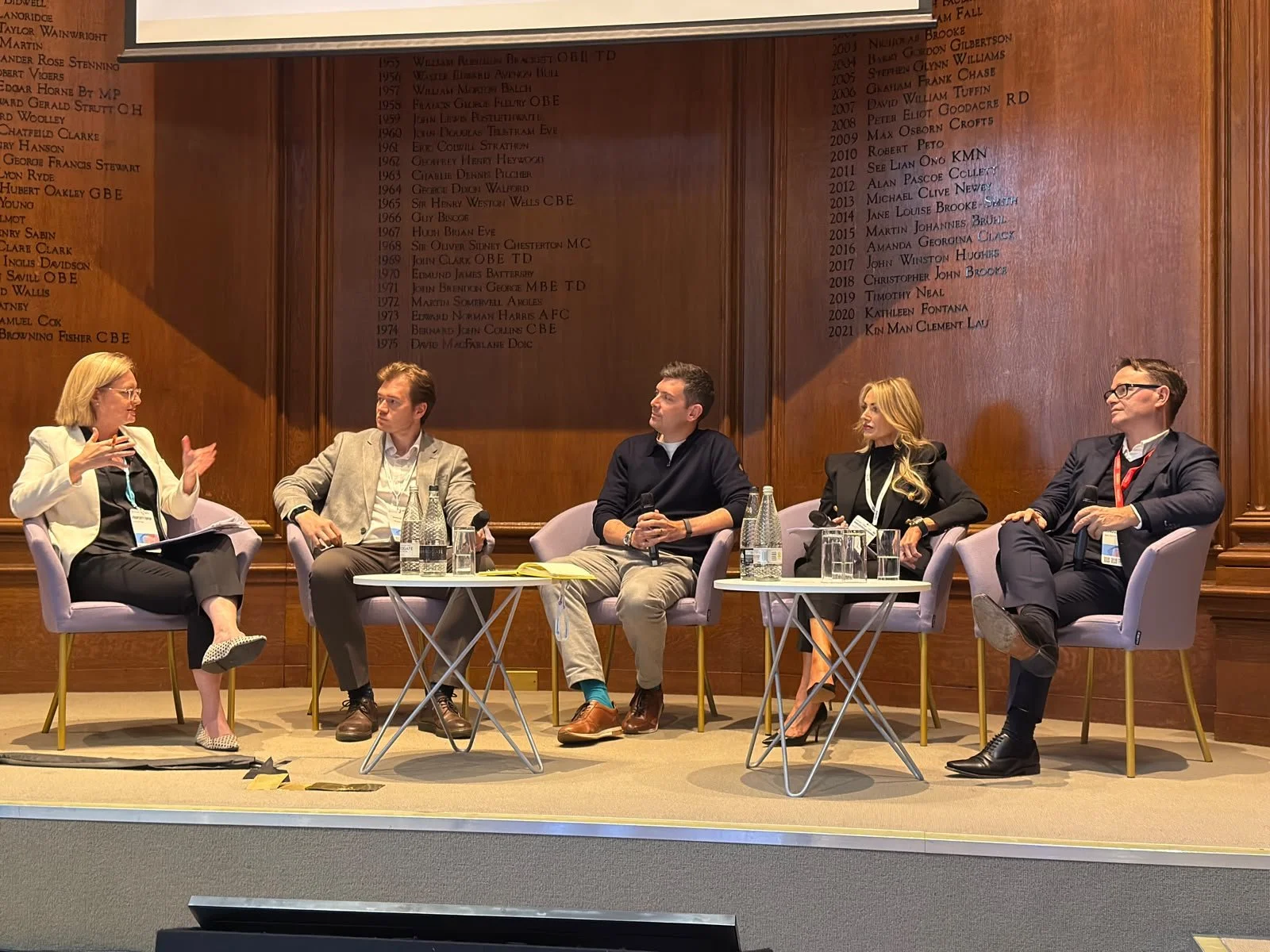 A panel of two women and three men sat on a stage at an investment event