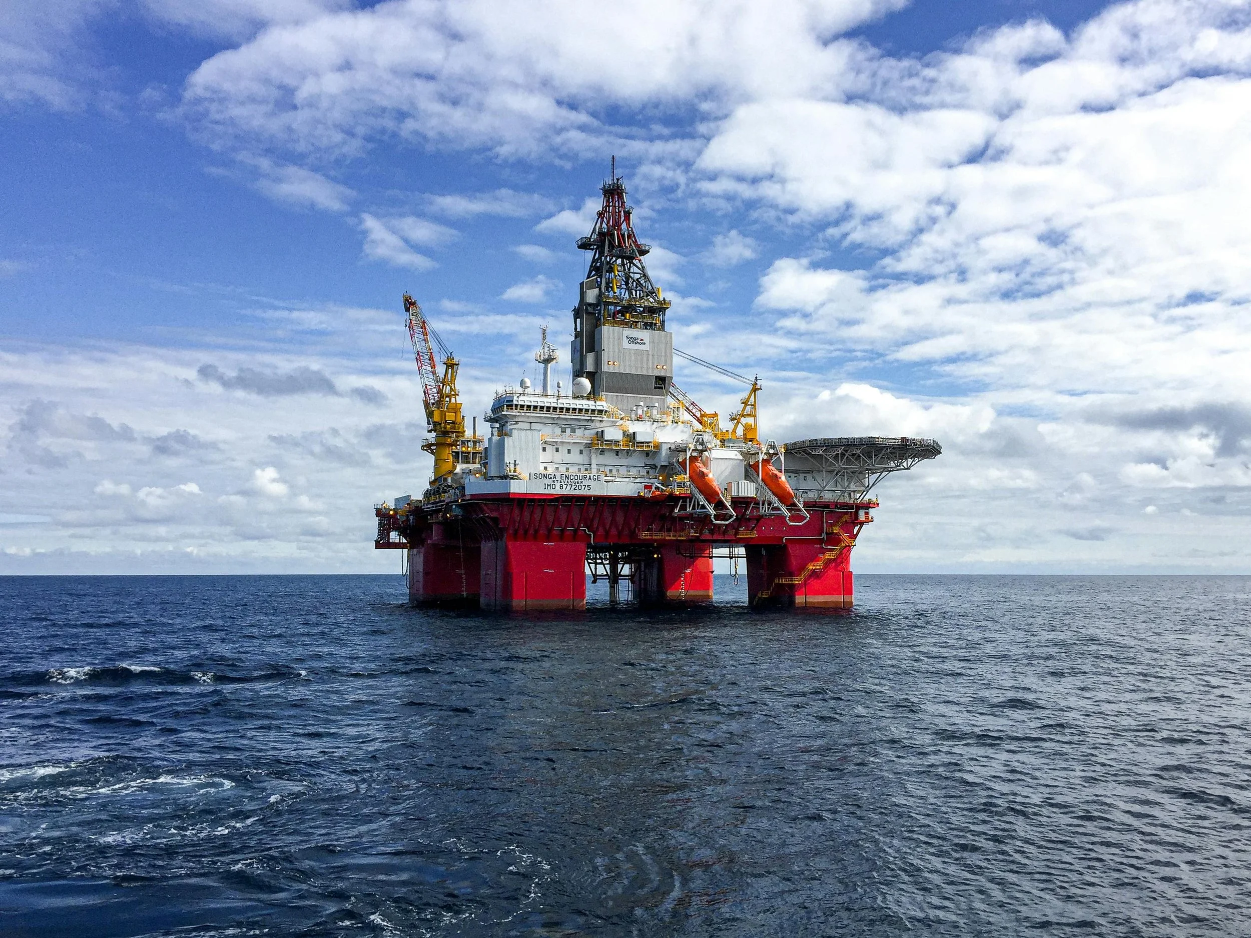 Offshore oil drilling platform in the ocean with a cloudy sky.