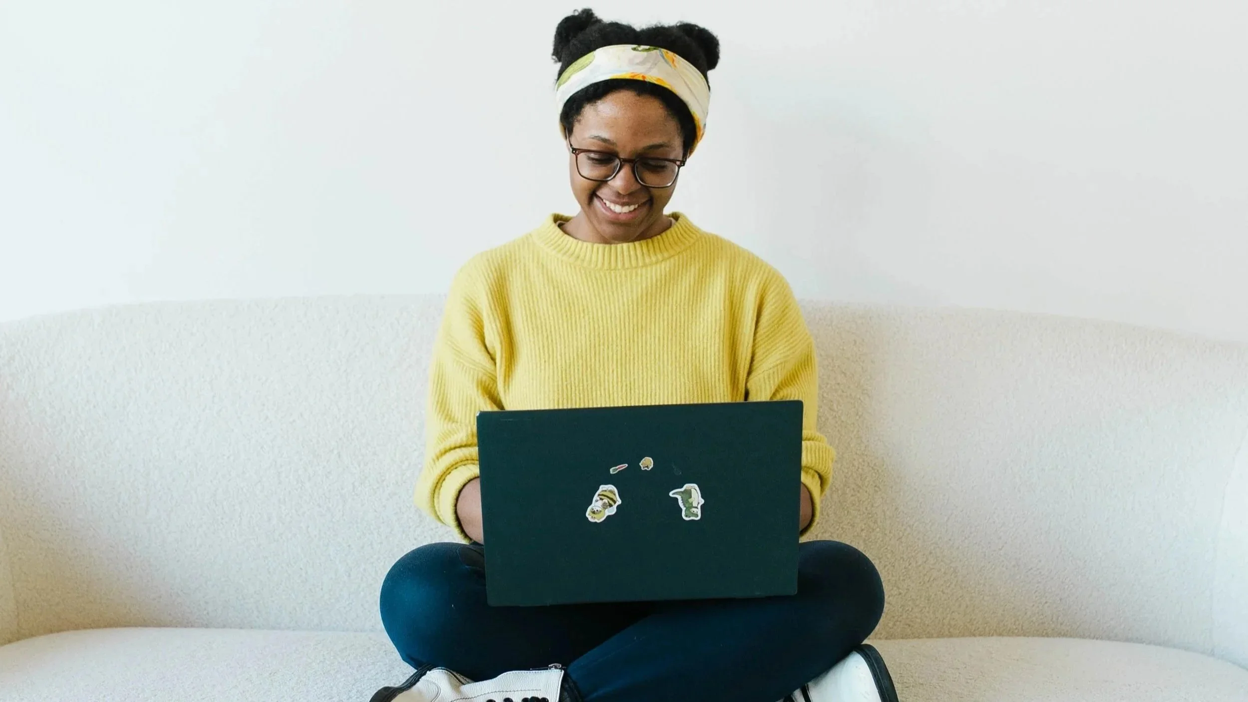Aneisha typing on a laptop while crosslegged on a couch
