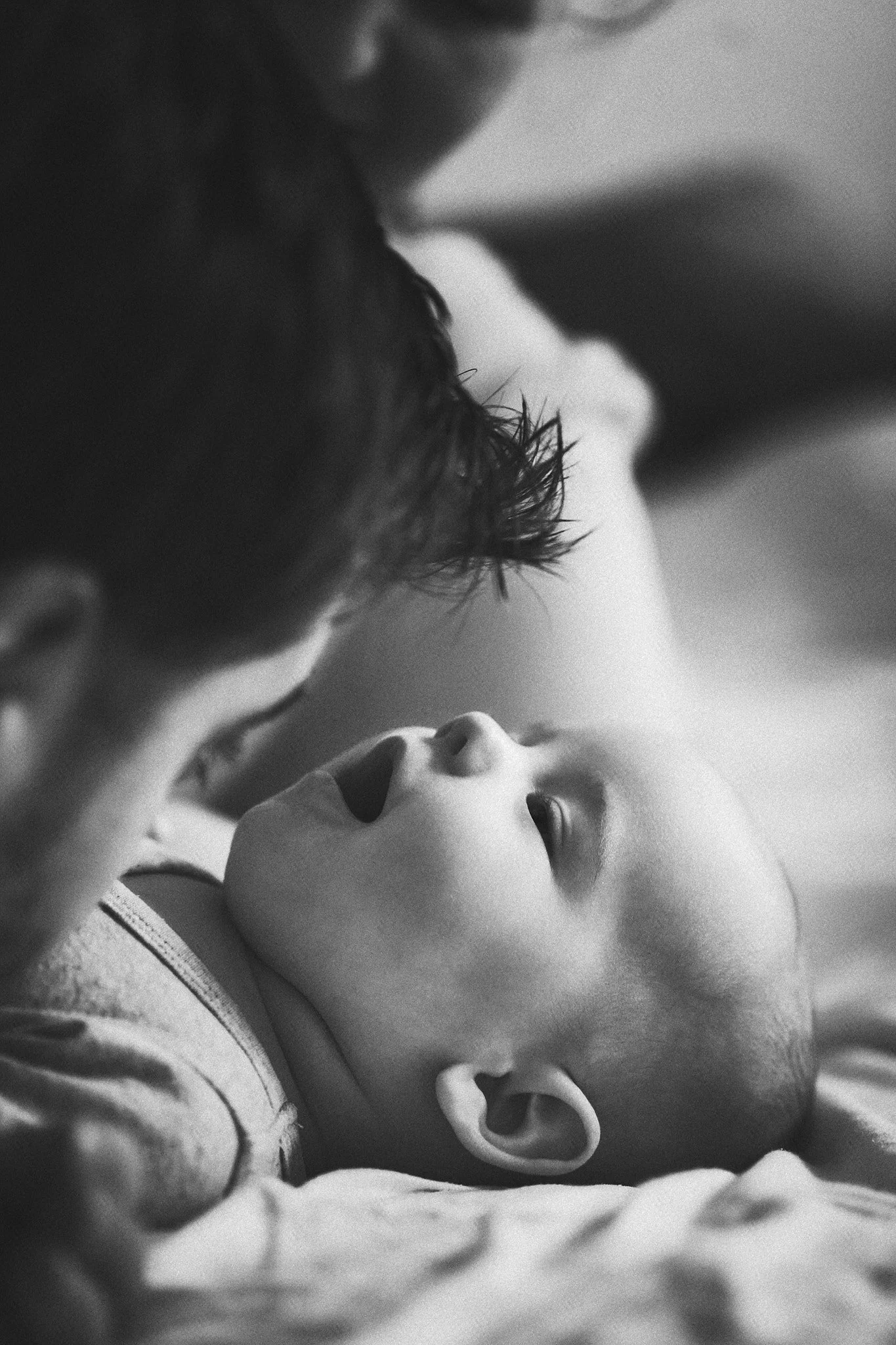 Nahaufnahme eines Babys, das auf einer Person liegt und an einer Puppe spaziert.