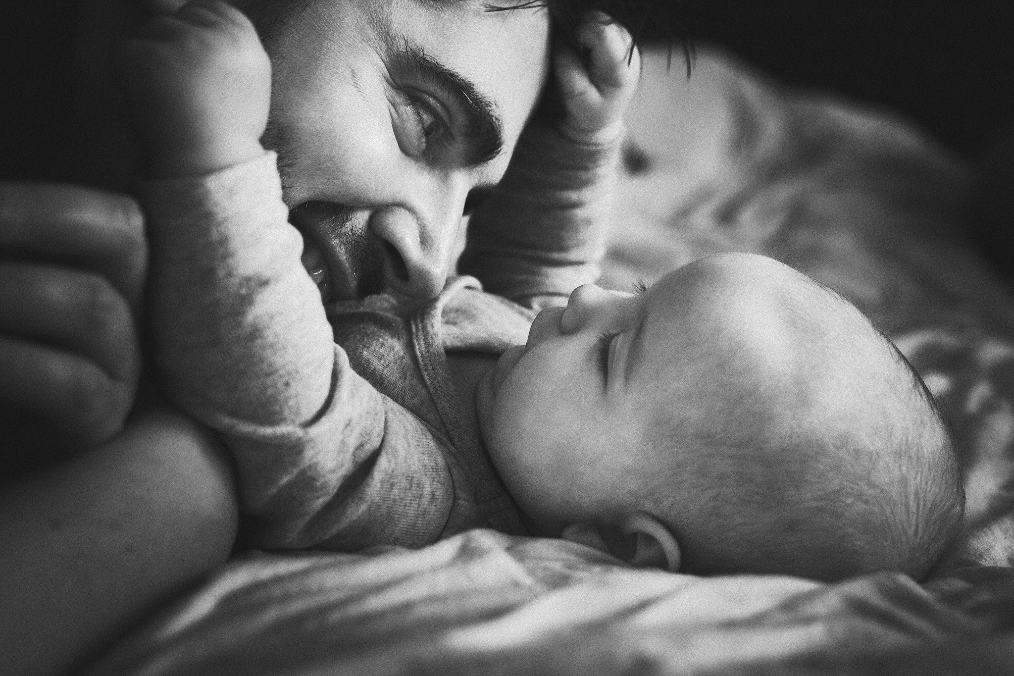 Nahaufnahme eines Mannes und eines Babys, die sich liebevoll berühren, in Schwarz-Weiß.