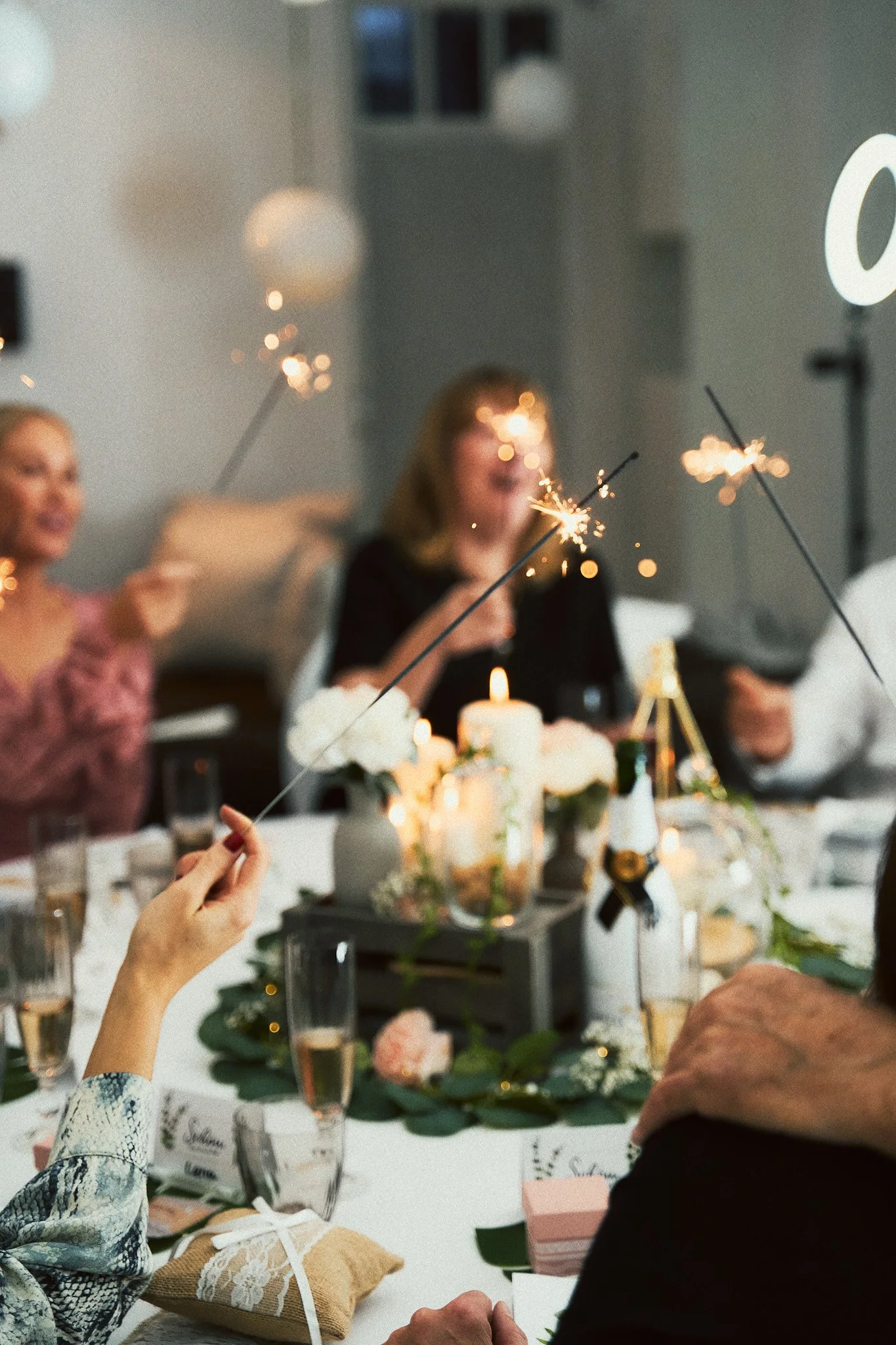 Menschen feiern eine Party mit Wunderkerzen und Kerzen auf einem festlich gedeckten Tisch.