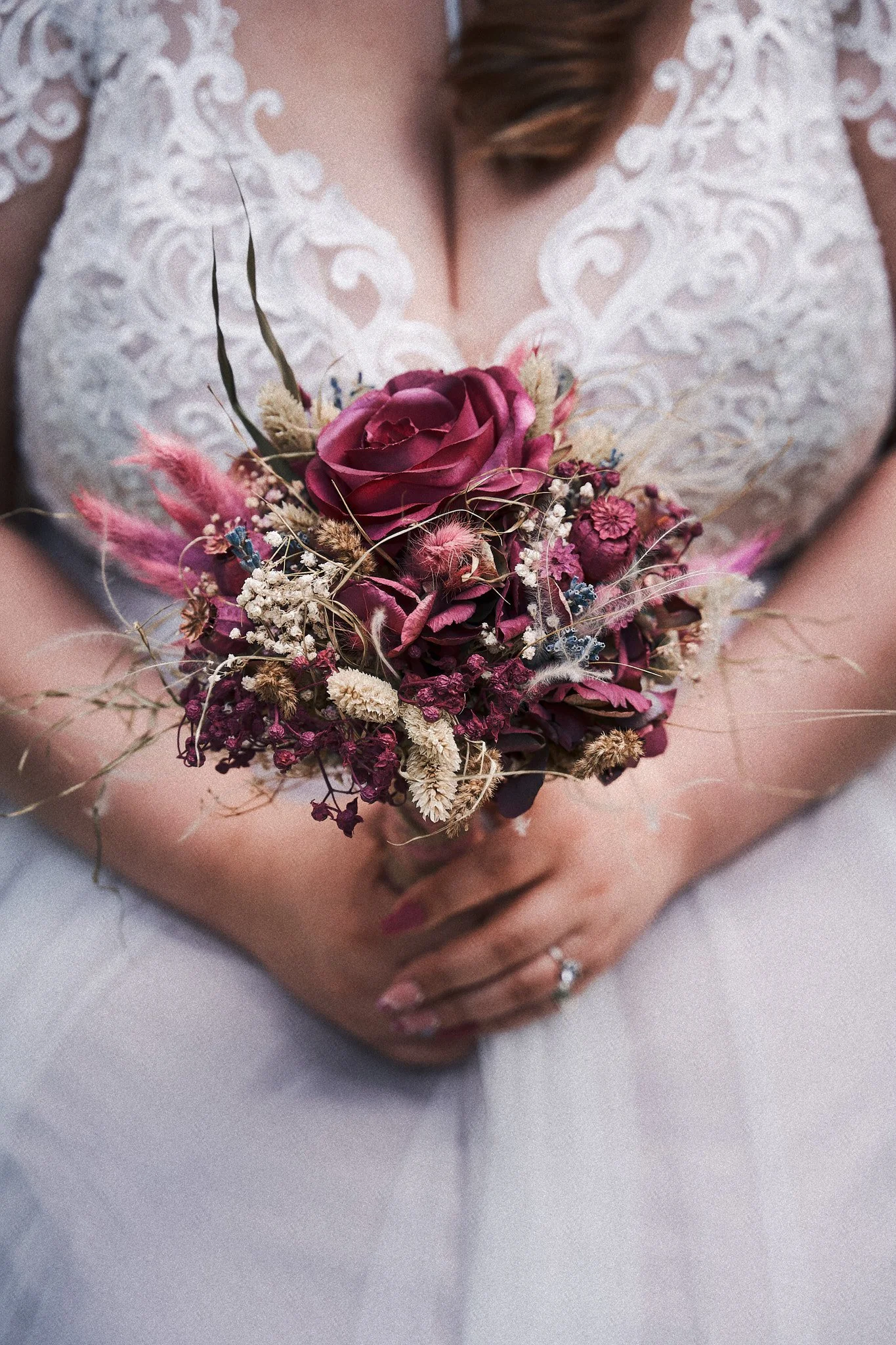 Nahaufnahme einer Braut, die ein Bouquet aus getrockneten Blumen hält, während sie ein weißes Hochzeitskleid trägt.