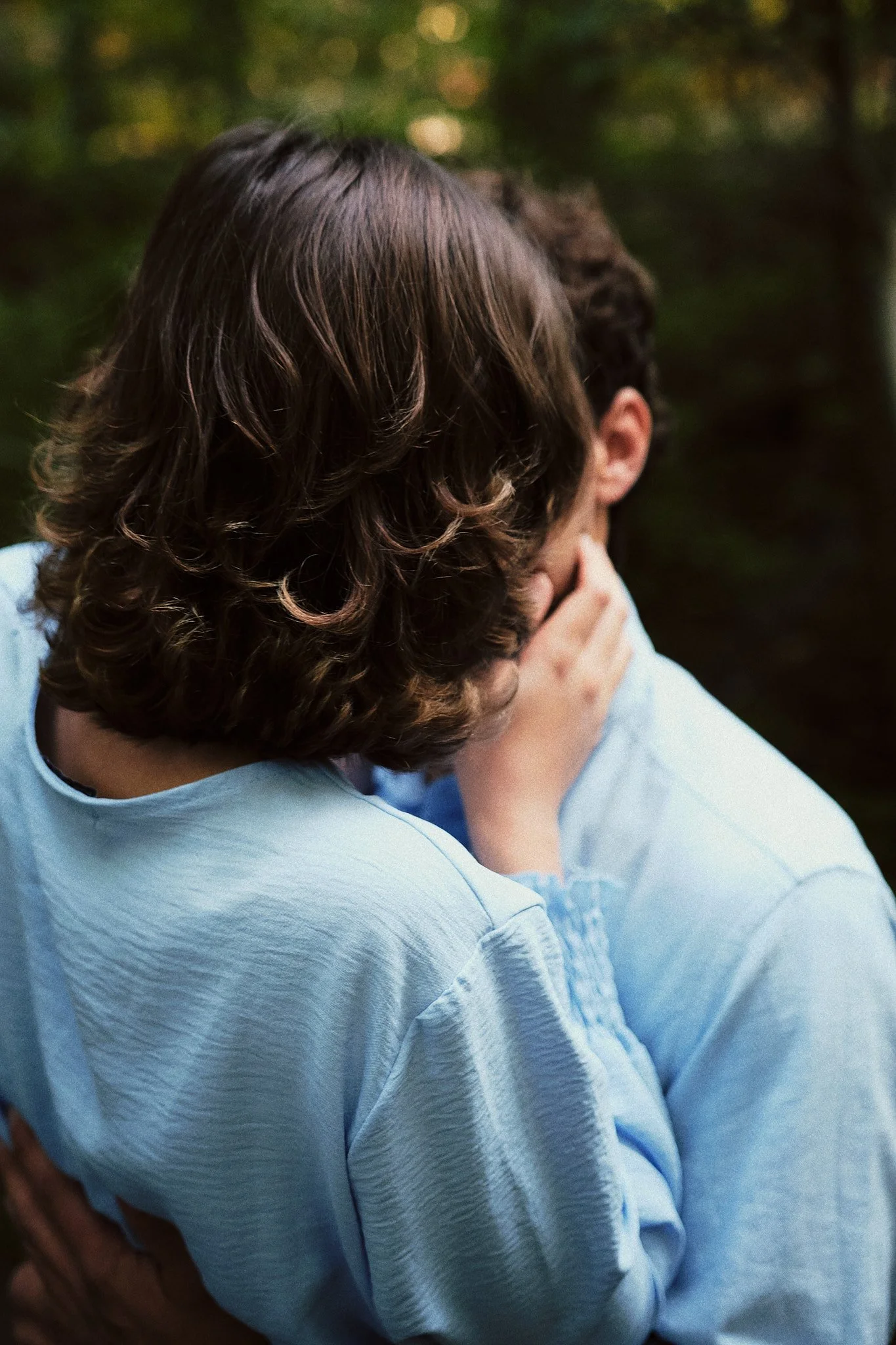 Zwei Kinder sitzen in einem Wald, eines tröstet das andere, das den Kopf in den Händen hält.