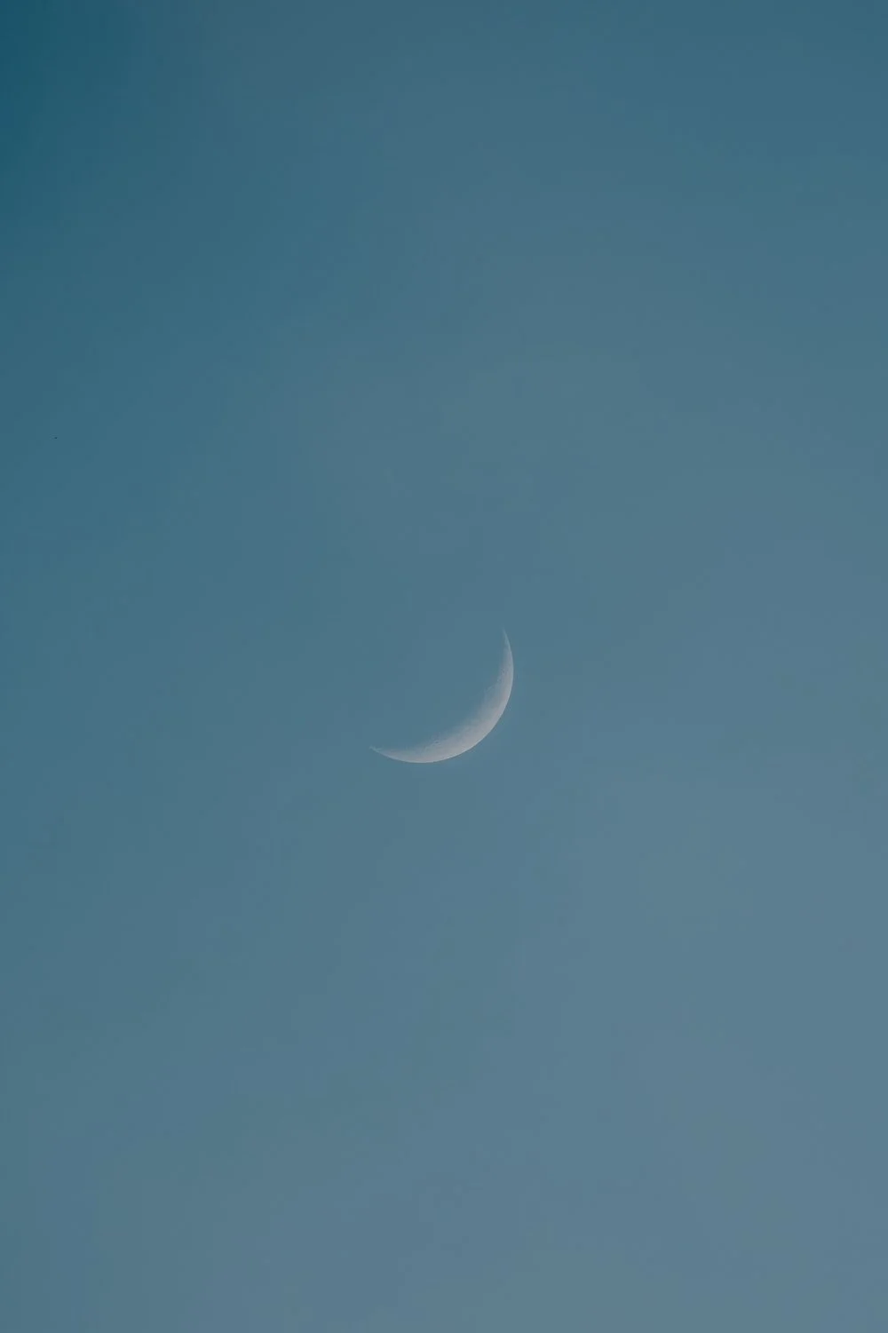 Der Himmel mit einer sichtbaren Mondsichel am Tag oder in der Dämmerung.