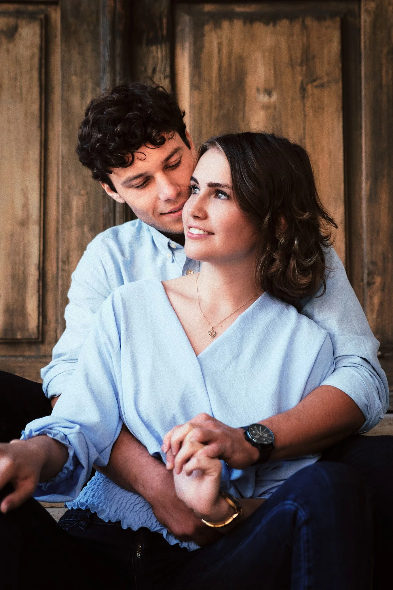 Ein glückliches Paar, das sich liebevoll umarmt, vor einer Holzwand.