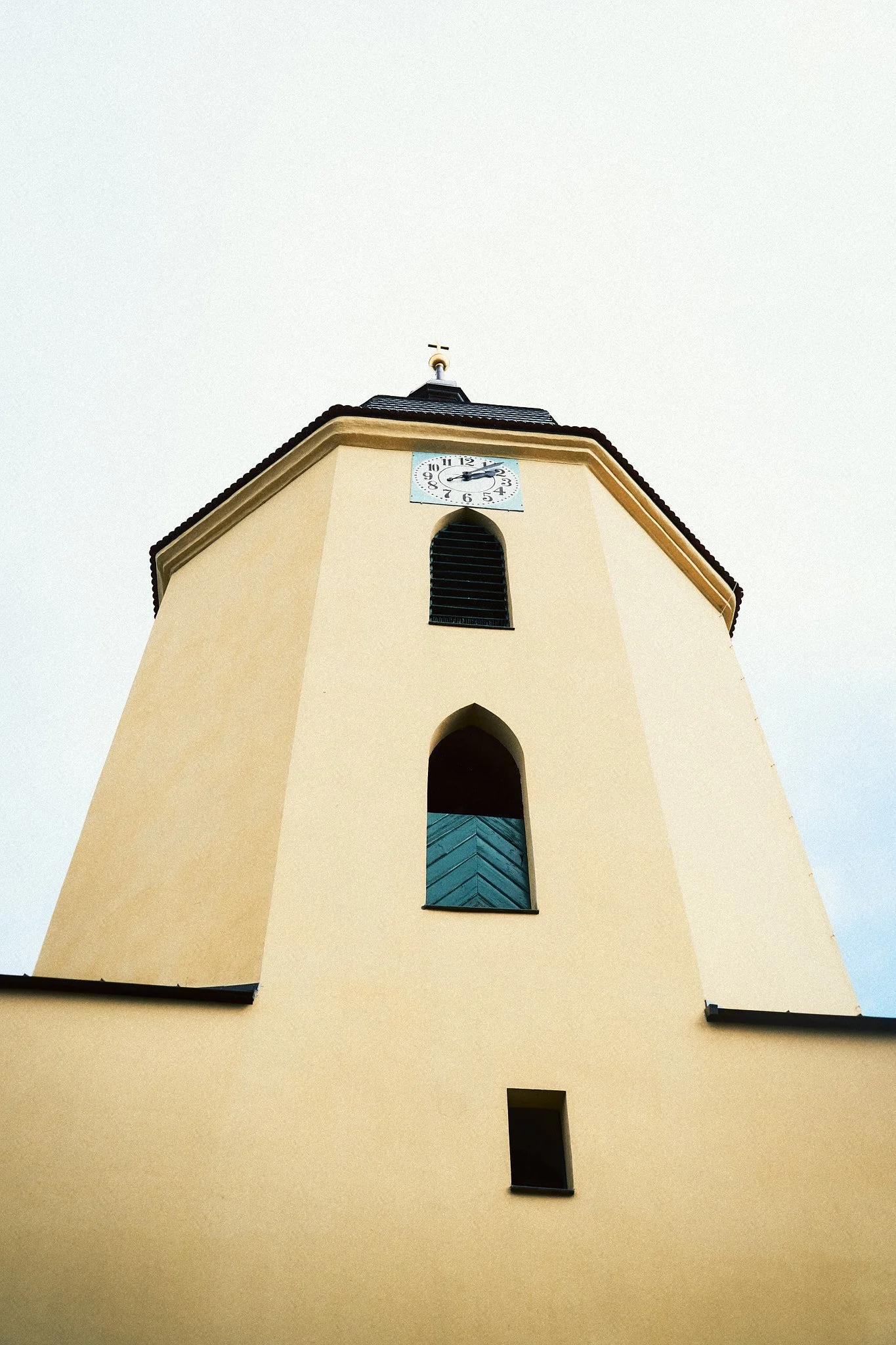 Bergkirche mit Uhrturm und schiefer Dach, Blick nach oben, klare Wolken am Himmel