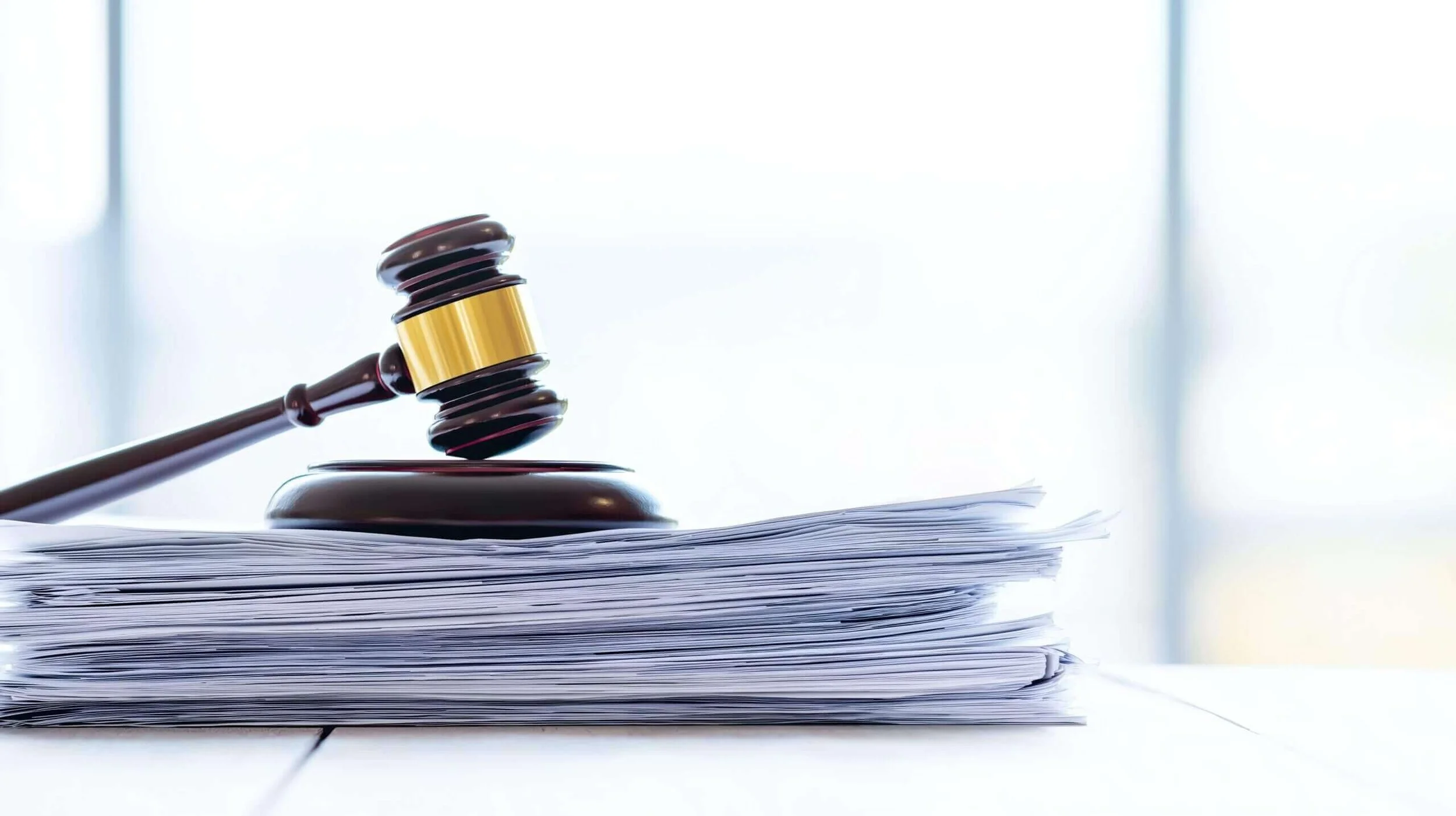 Gavel resting on a pile of papers, symbolizing law or legal proceedings.
