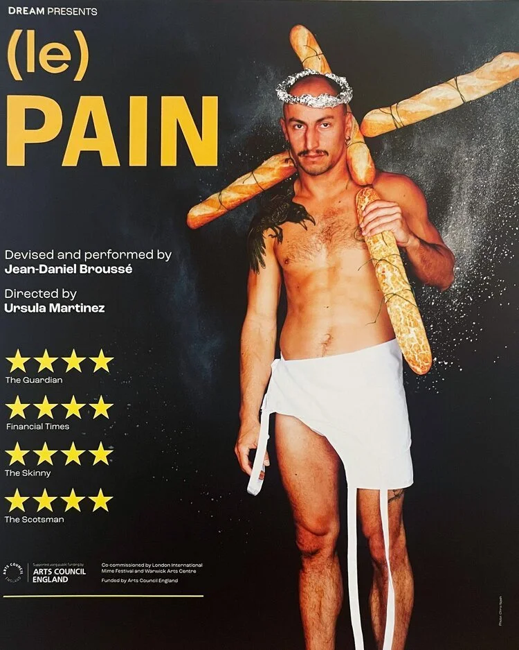 Poster for a performance titled 'Pain' by Jean-Daniel Broussé, directed by Ursula Martinez. The image features a shirtless man with a white loincloth, a graham cracker on his head with a halo, and breadsticks or baguettes as weapons on his shoulders.