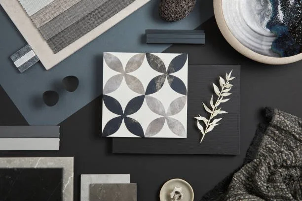 A collection of design and decor items including tiles, fabric swatches, a leaf, and a bowl with abstract objects.