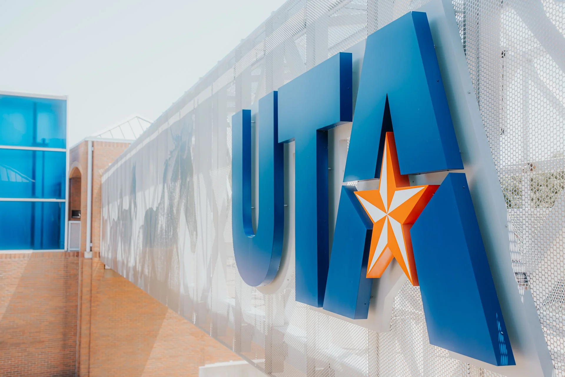 UCLA sign with a star logo on a perforated metal panel wall outside building.