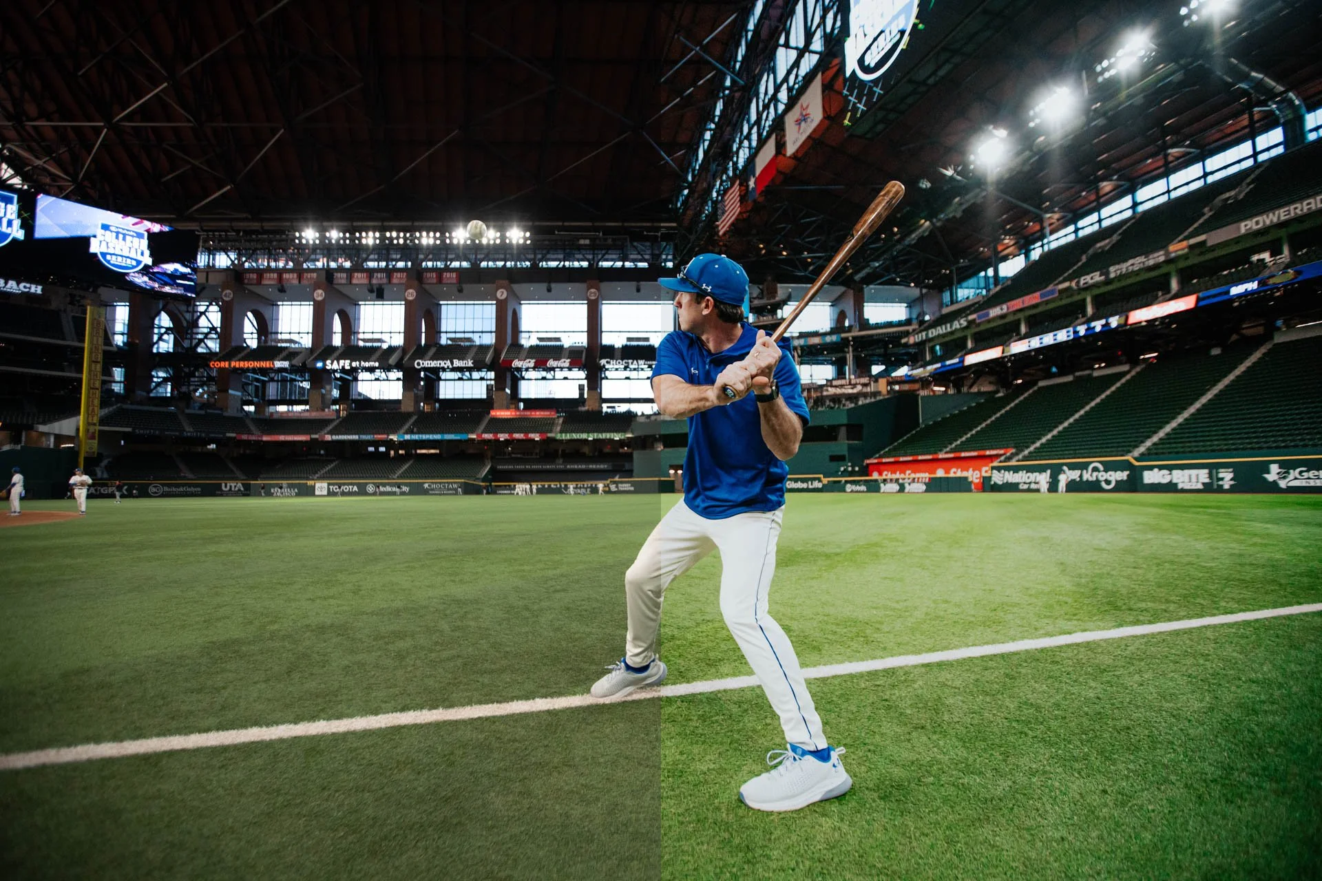A man in a blue shirt, white pants, and a blue cap prepares to bat in an empty stadium.