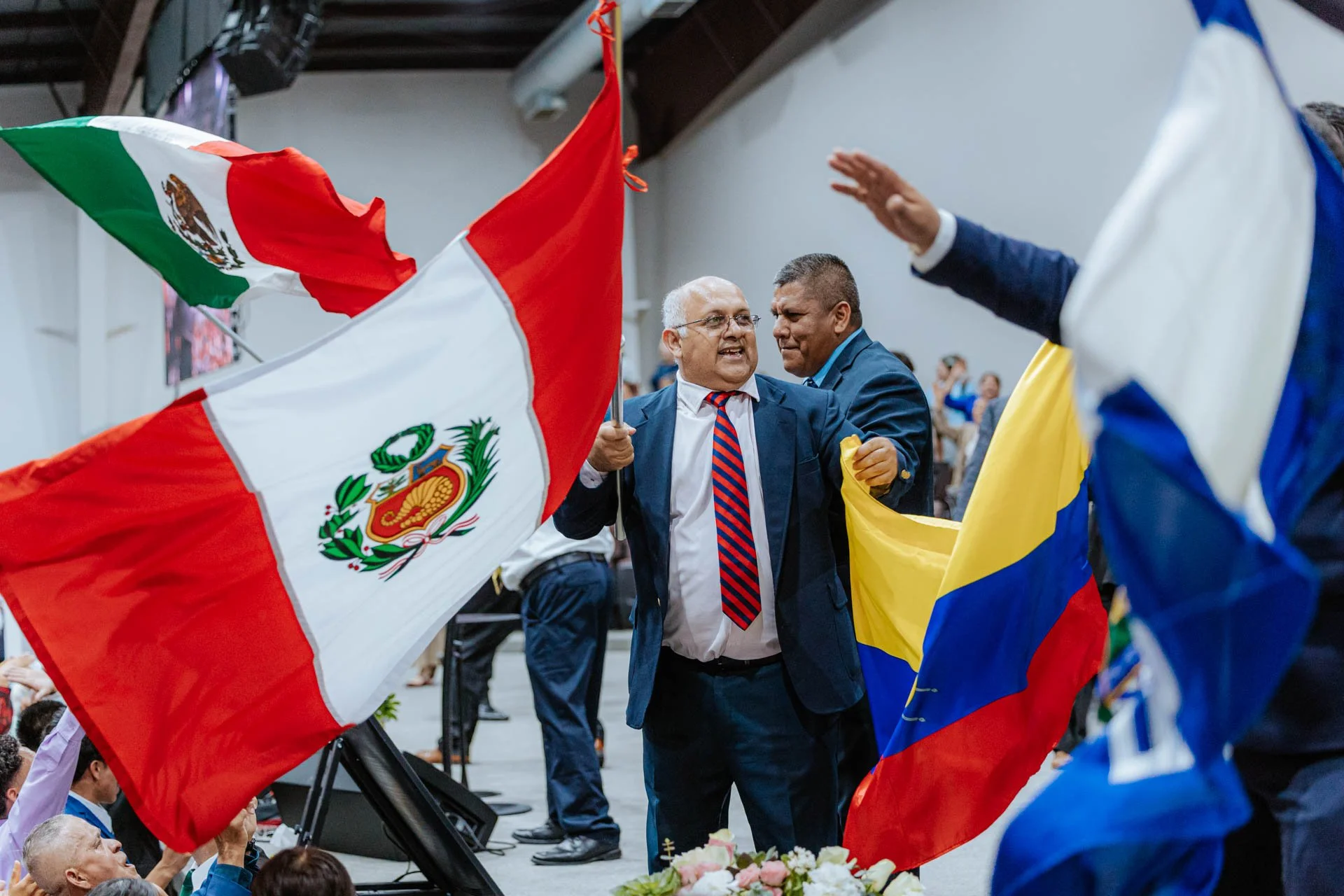 People celebrating with flags from Mexico and Colombia at an event.