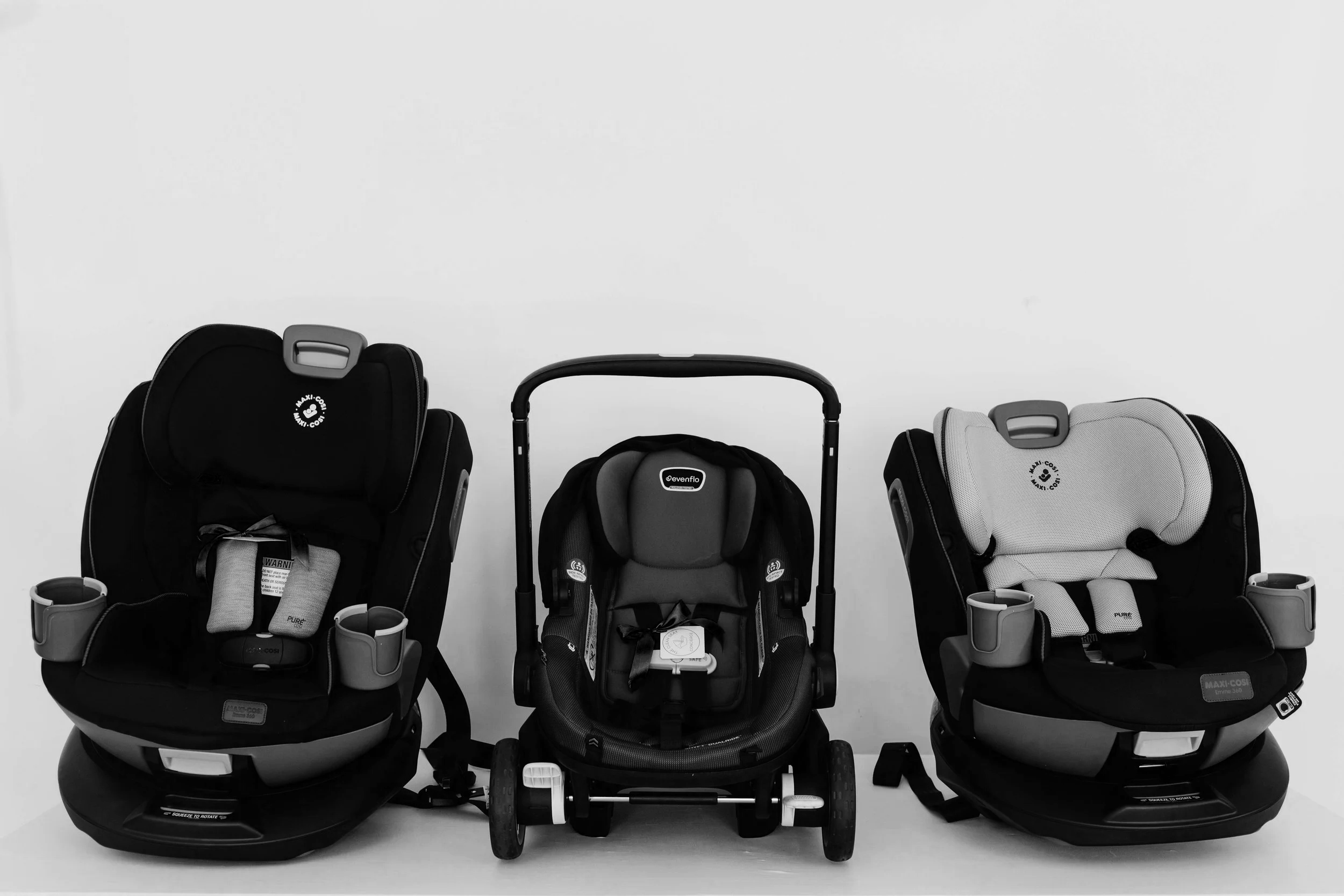 Three child car seats arranged in a line on a white background, with the middle one being a stroller. The left and right seats are adult-sized car seats for children, while the middle one is a smaller seat on wheels.